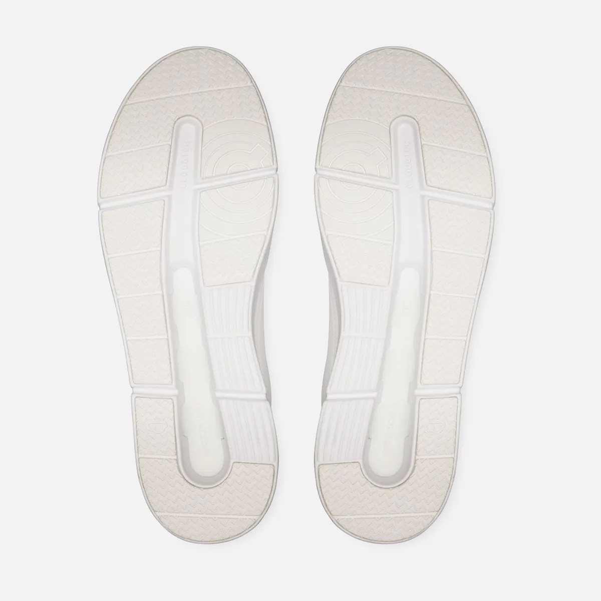 Pair of white shoe soles with textured grip patterns and a central groove running lengthwise.