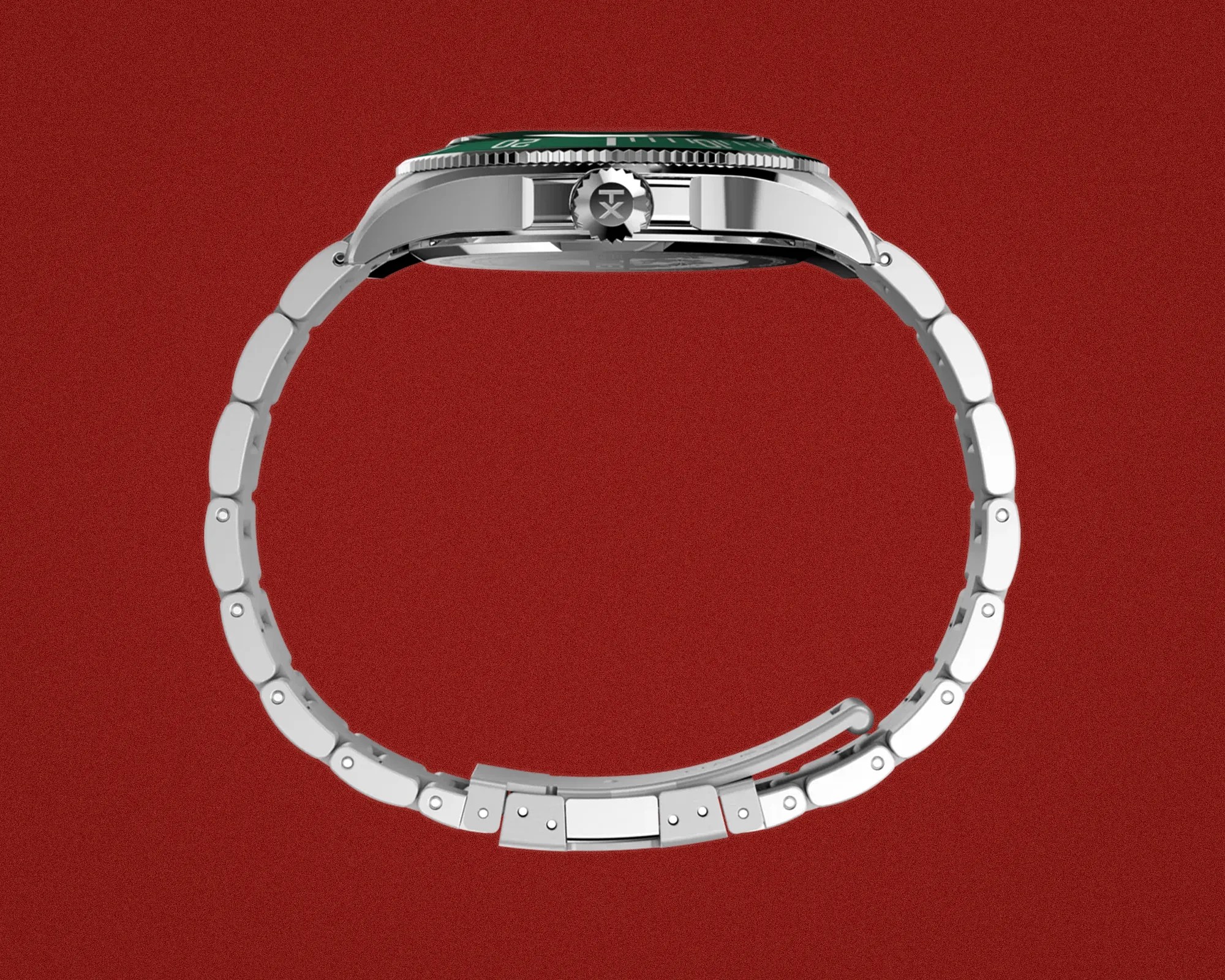 Silver metal wristwatch with a green bezel shown from the side on a red background.