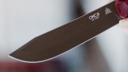 Close-up of a black OKC 25-1000 knife blade with a sharp edge and a red handle.