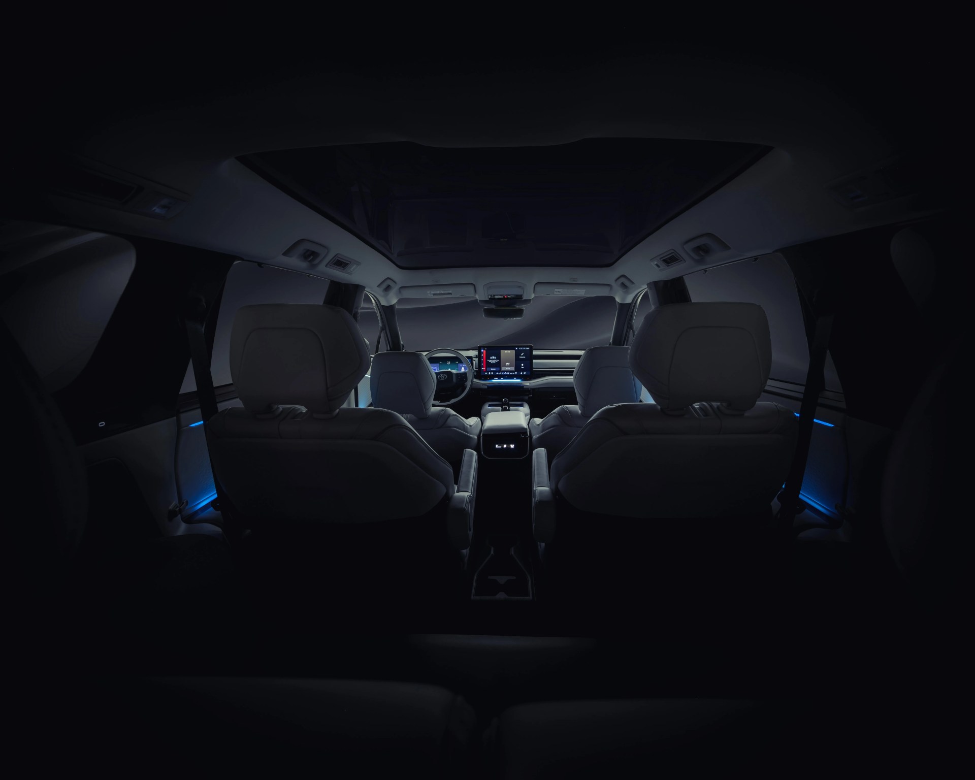 Interior view of a modern car with illuminated dashboard, touchscreen display, and ambient blue lighting.
