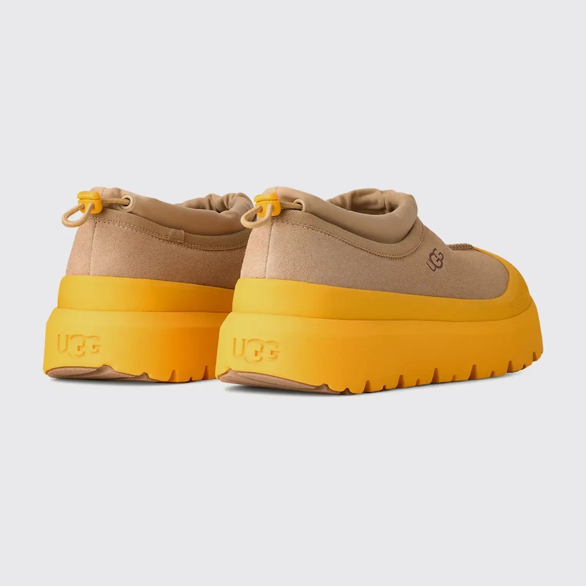 Pair of tan suede UGG sneakers with thick bright yellow soles and yellow pull tabs at the heel.