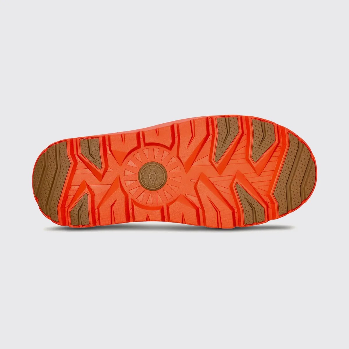 Orange and brown rubber shoe sole with deep treads and UGG logo in the center.
