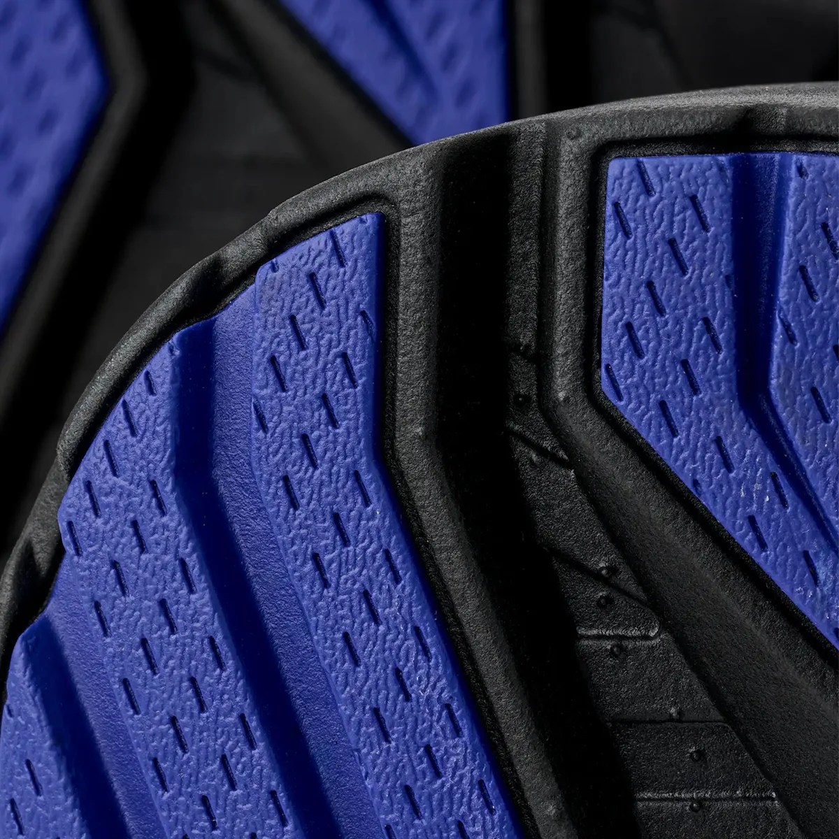 Close-up of a black and blue textured rubber shoe sole with grooves and patterns.