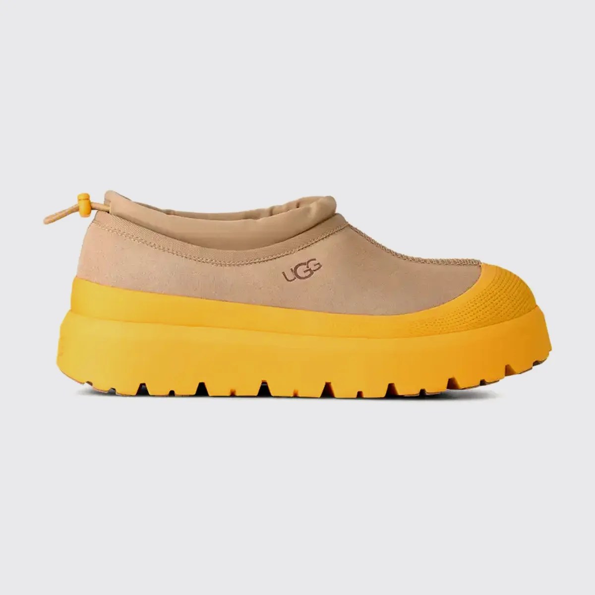 Tan slip-on shoe with bright yellow thick sole and toe cap, featuring UGG logo on the side.