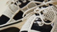 Close-up of black and beige knit sneakers with beige laces and perforated details.