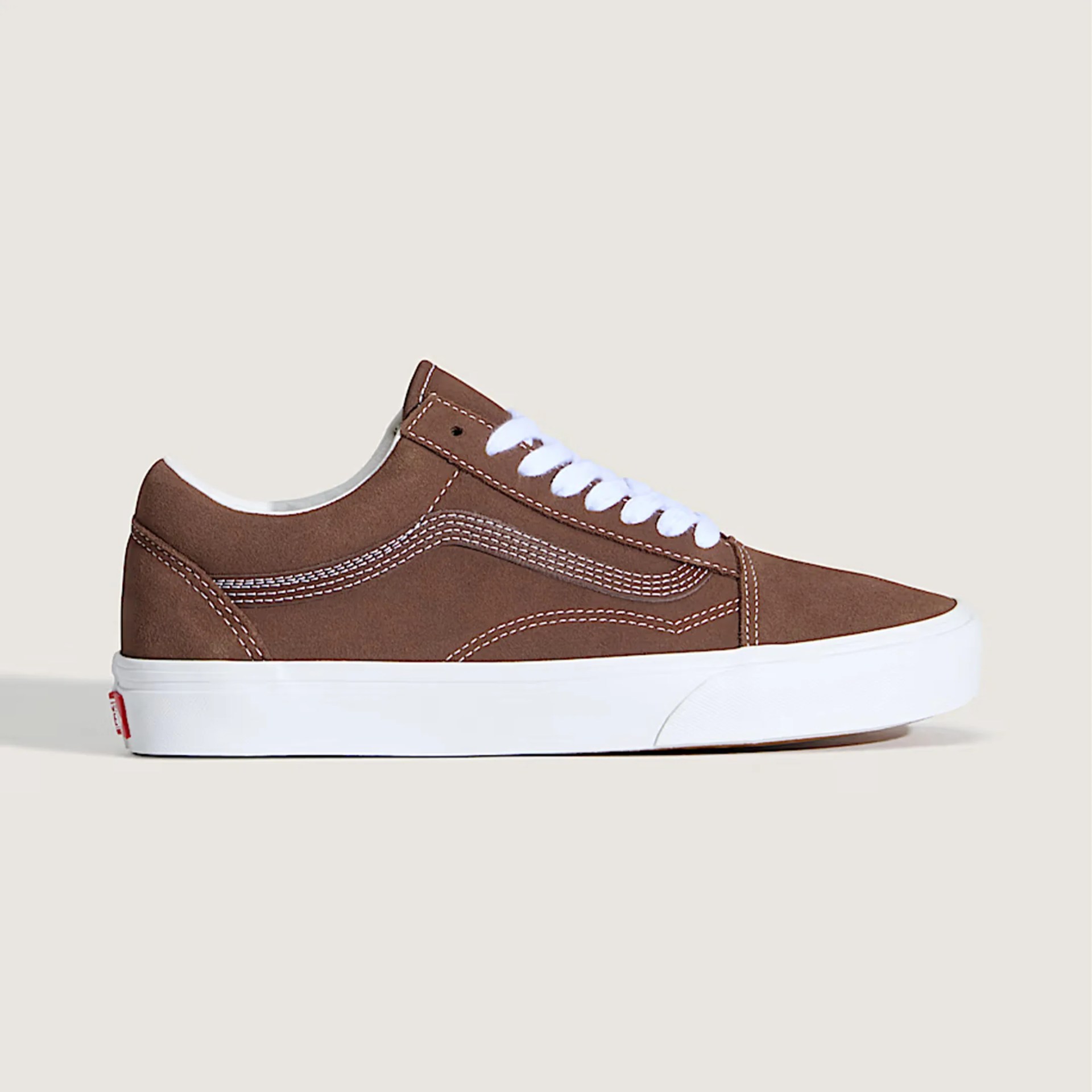 Brown suede low-top sneaker with white laces and thick white rubber sole on a beige background.