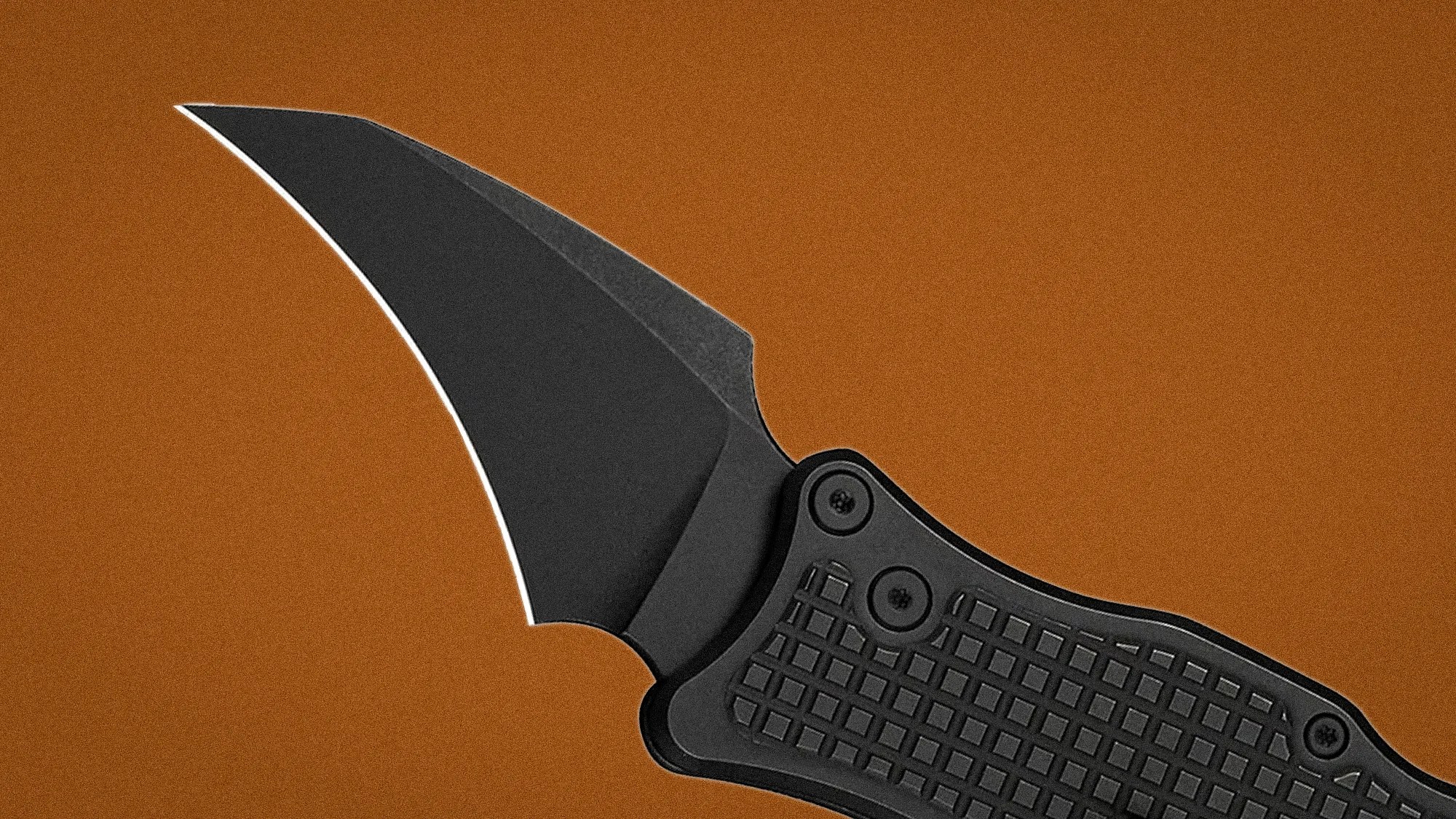 Black folding knife with a curved blade and textured handle on a brown background.