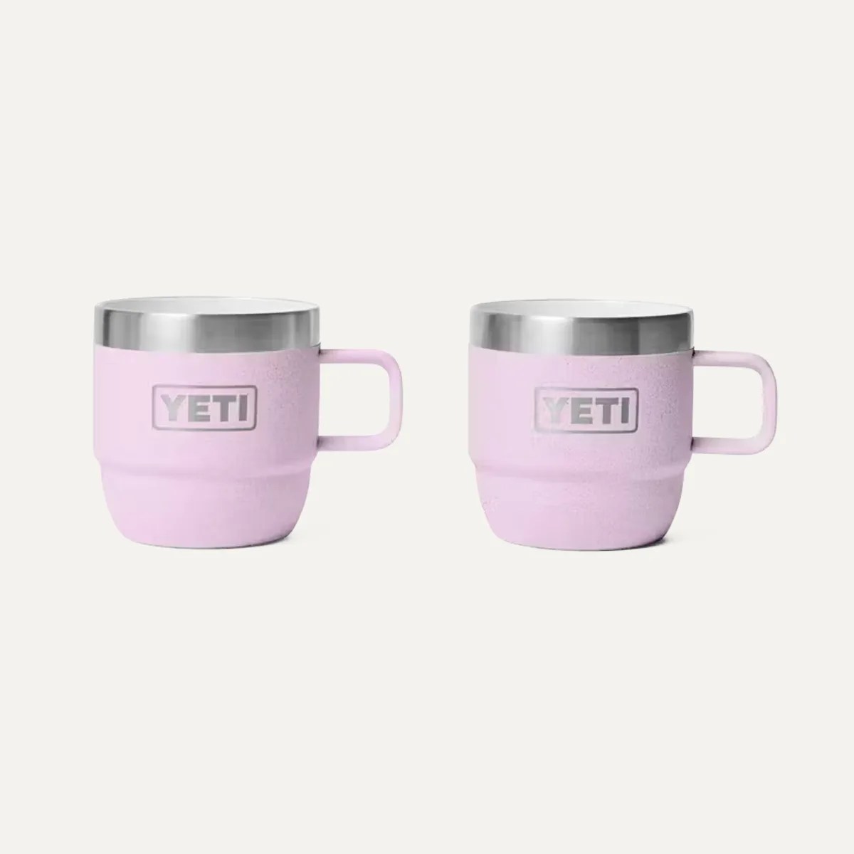 Two pink YETI insulated mugs with stainless steel rims and handles on a white background.