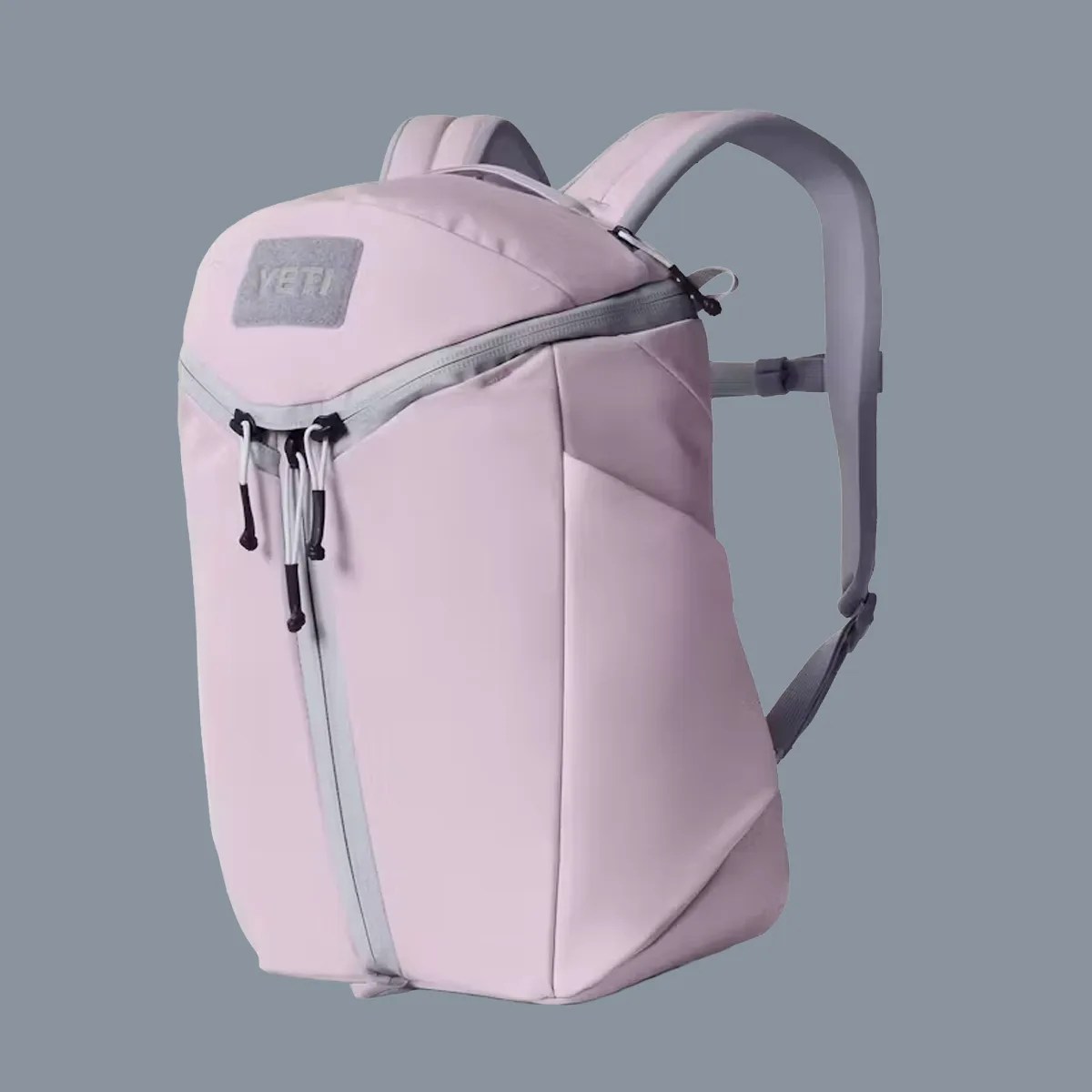 Light pink YETI backpack with gray zipper and padded shoulder straps against a gray background.