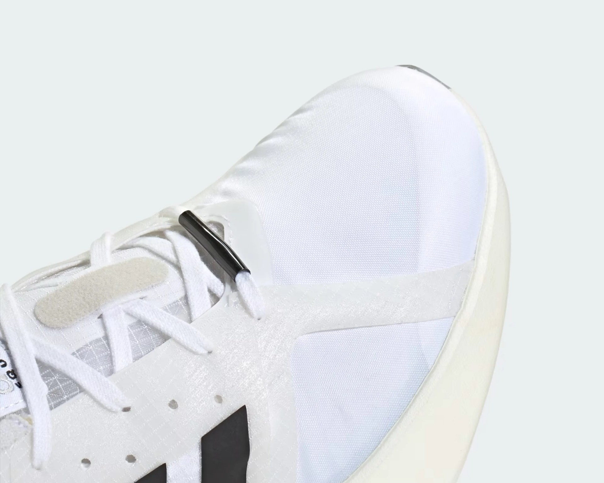 Close-up of the front part of a white athletic shoe with black stripes and white laces.