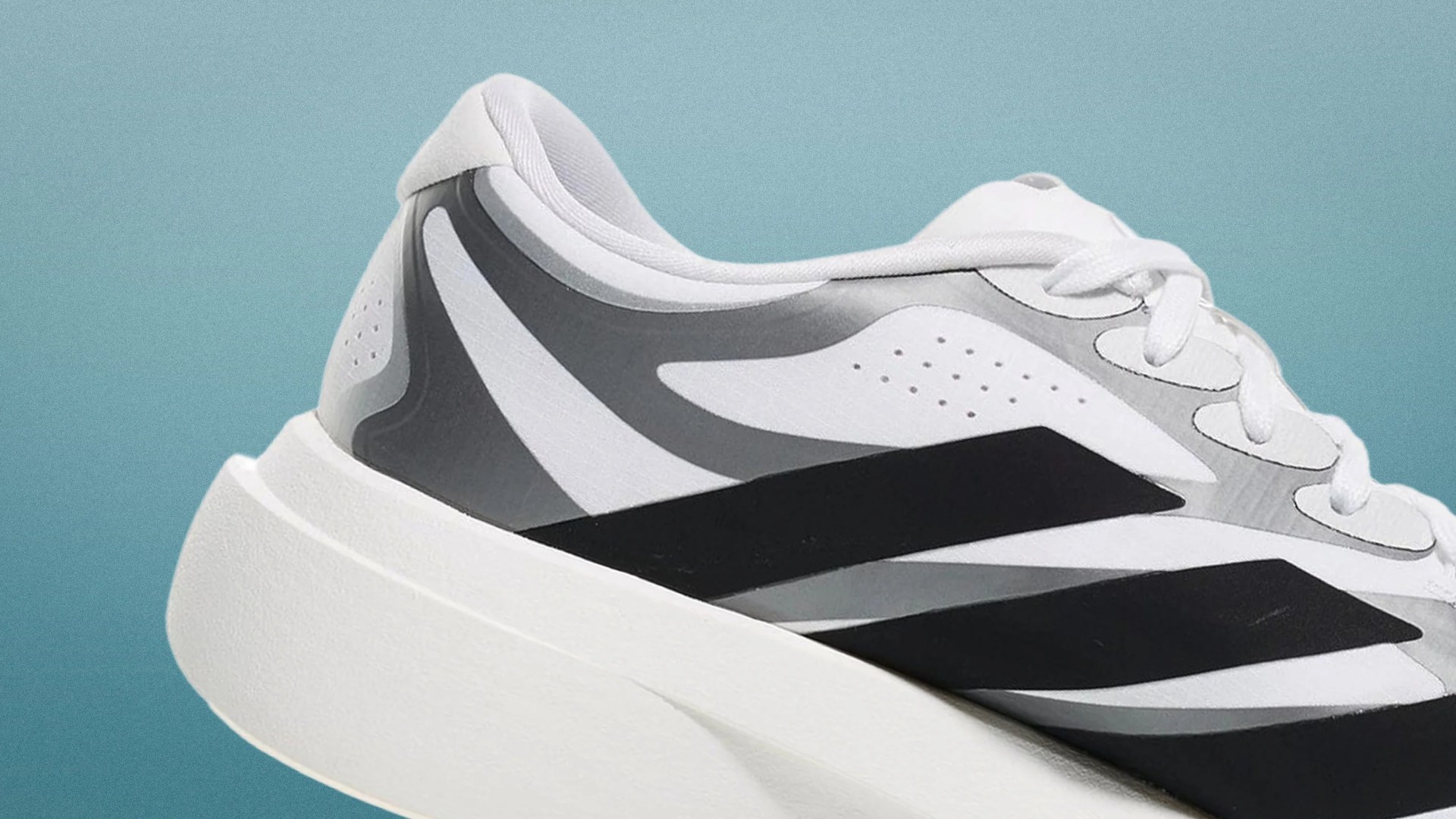 White and gray athletic shoe with black geometric stripes and thick white sole.