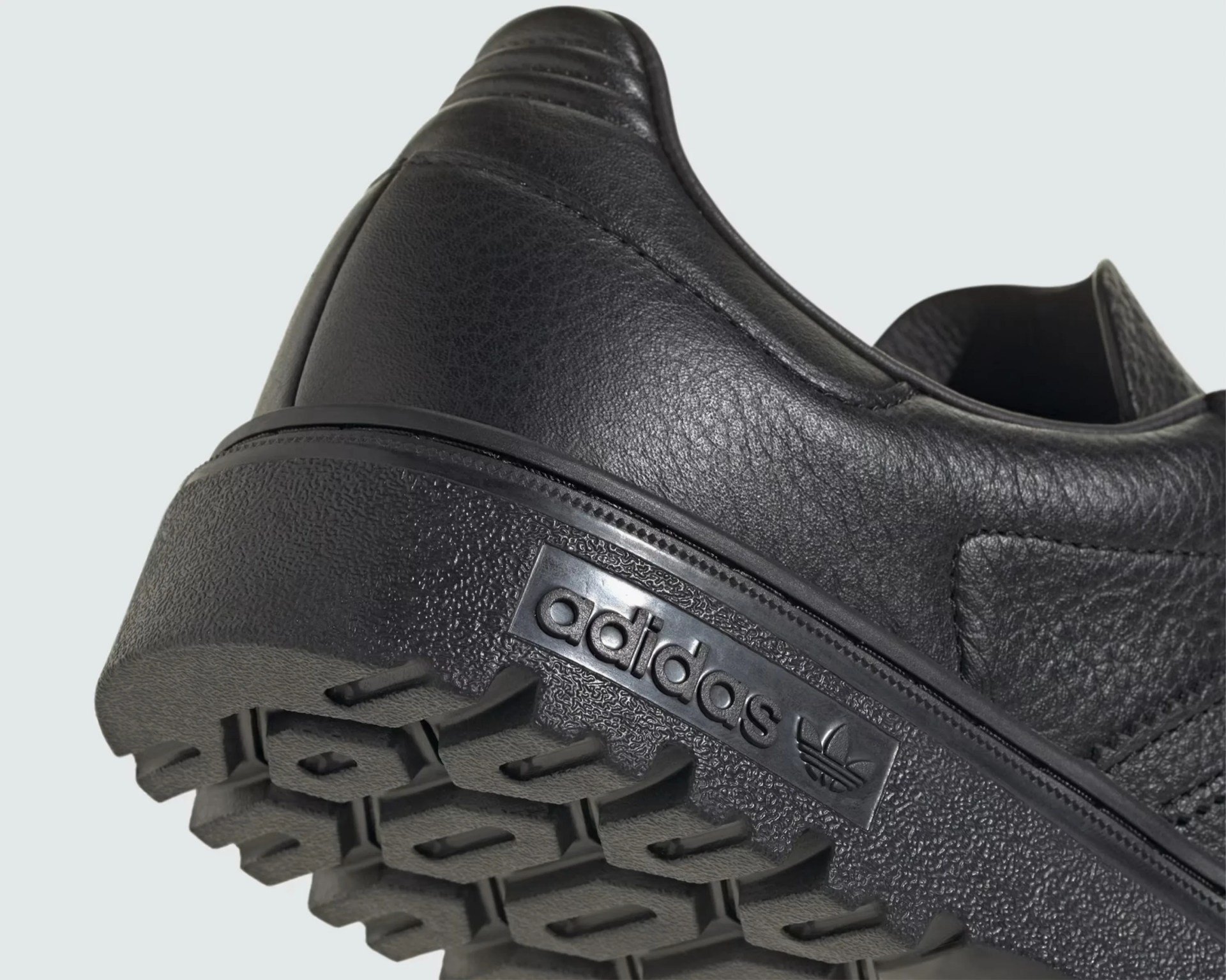 Close-up of the black leather Adidas sneaker heel with textured sole and embossed logo.