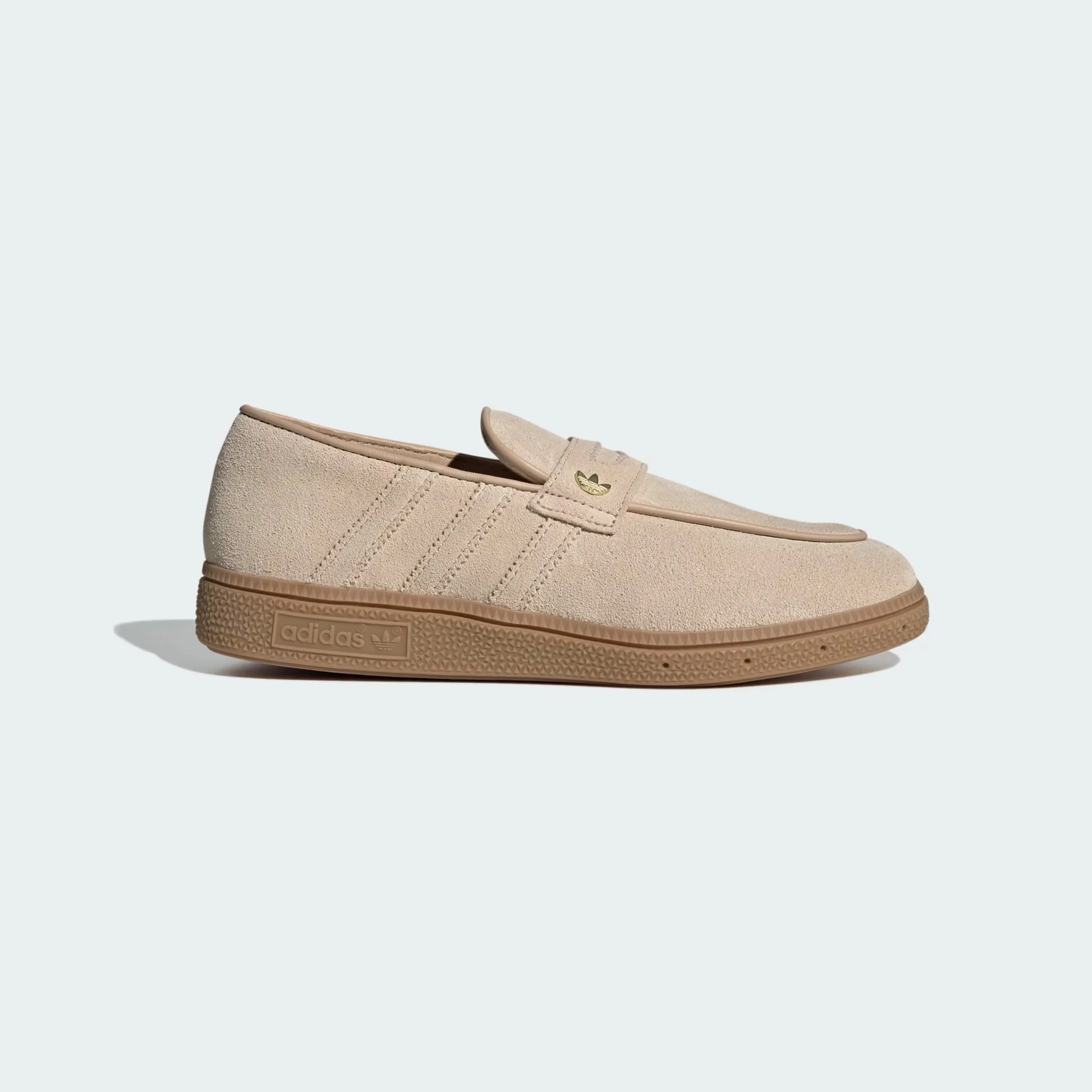 Beige suede Adidas loafer with gum sole and gold Adidas logo on strap.