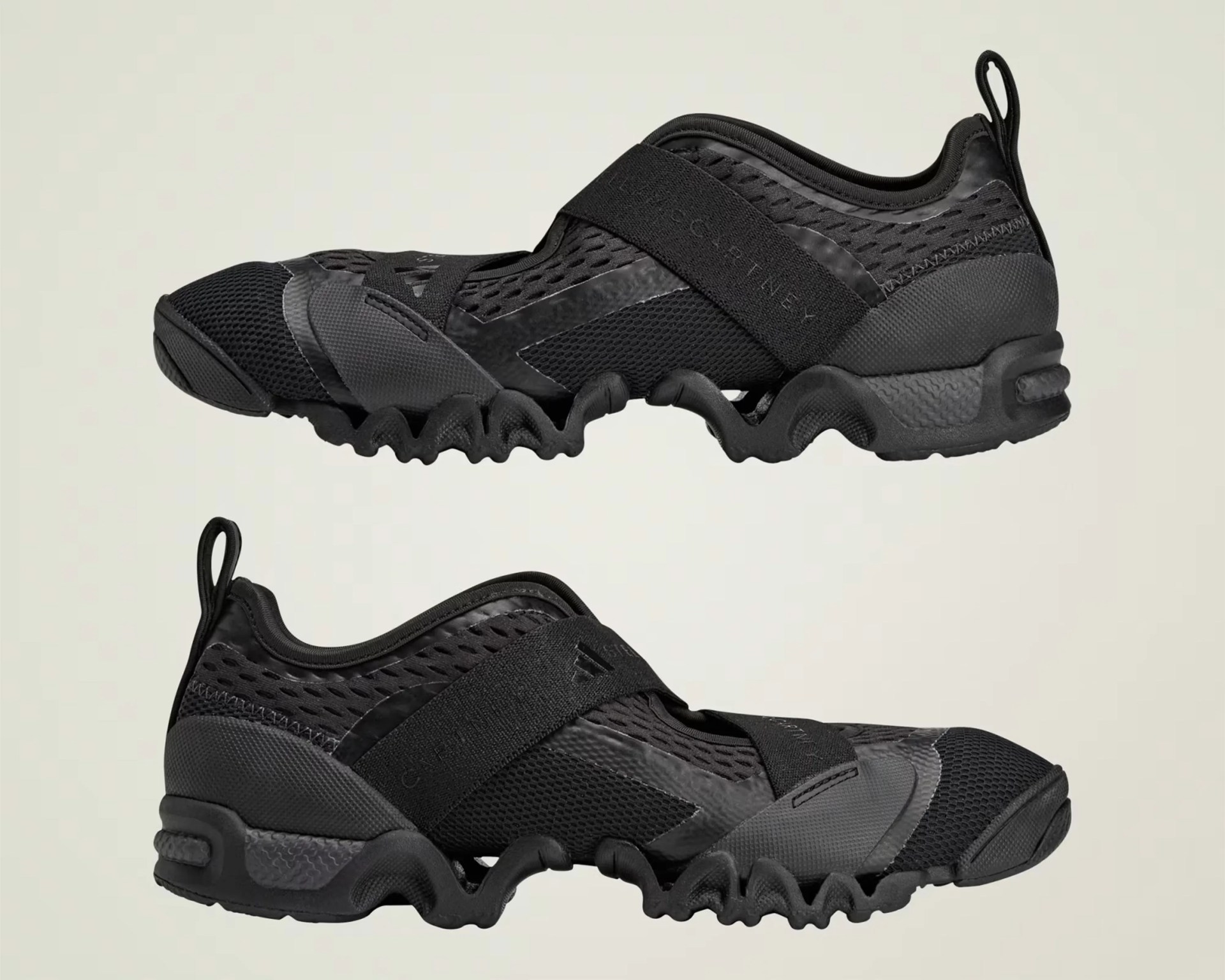 Pair of black athletic shoes with wavy soles and wide elastic straps across the top.