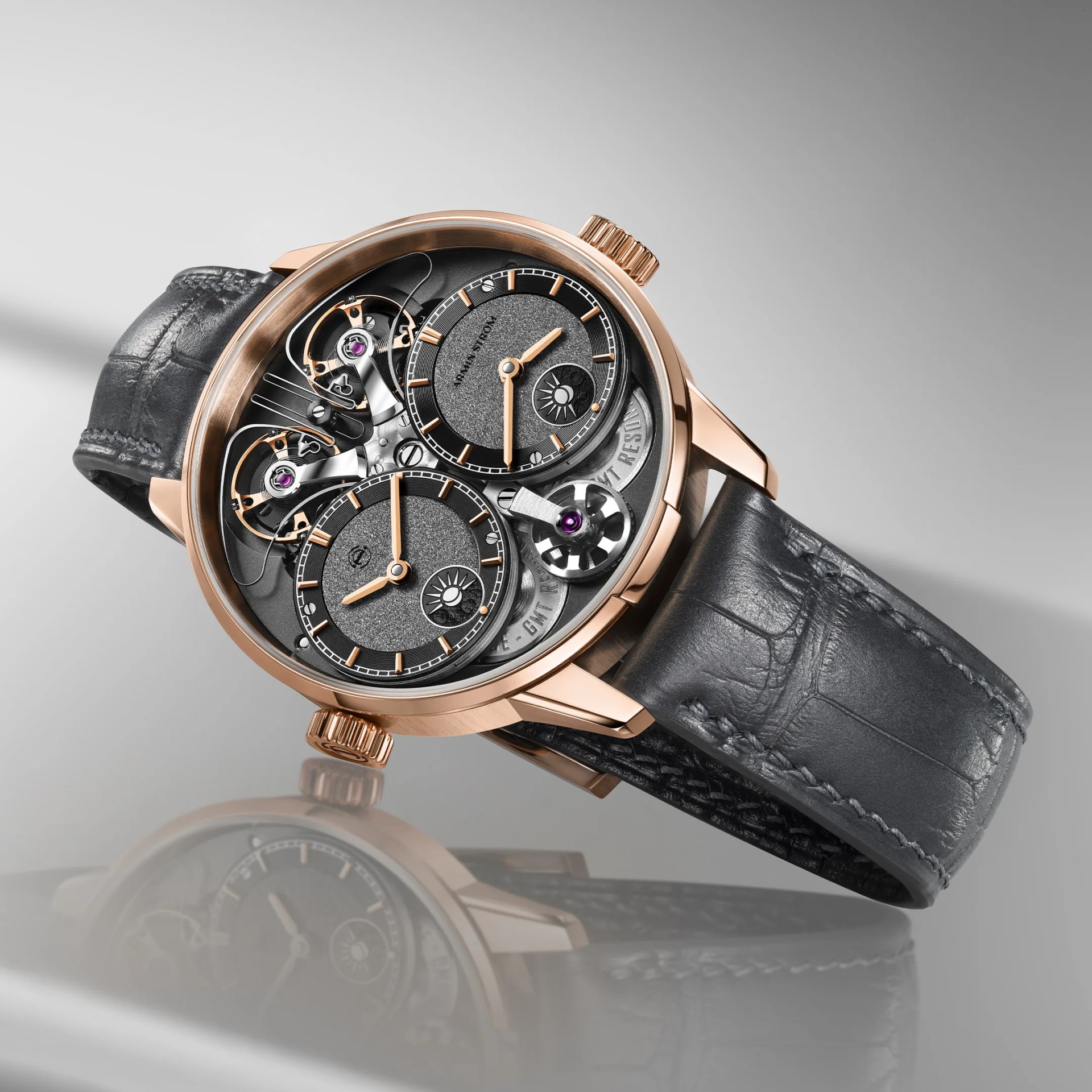 Rose gold wristwatch with dual black textured dials, visible mechanical components, and a black leather strap.