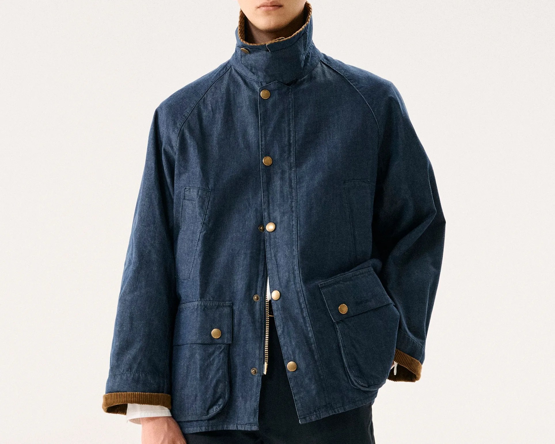 Navy blue jacket with high collar, brass snap buttons, and large front pockets worn by a person.