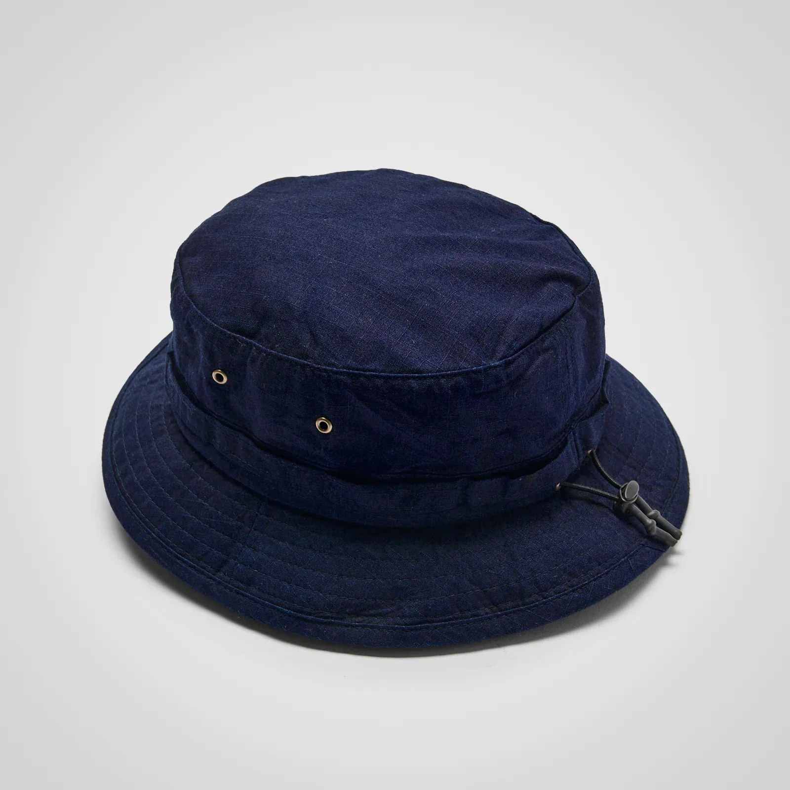 Navy blue bucket hat with metal eyelets and adjustable cord on a white background.