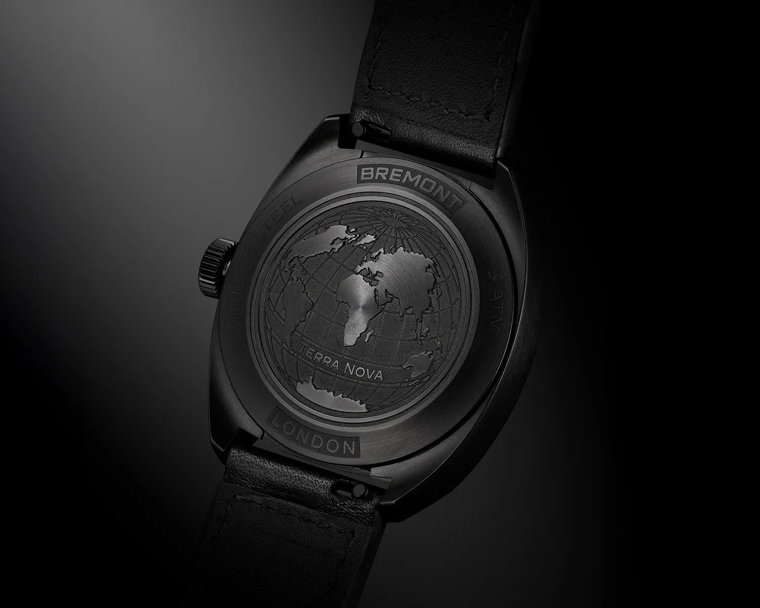 Back of a black Bremont Terra Nova watch with engraved world map and black leather strap.