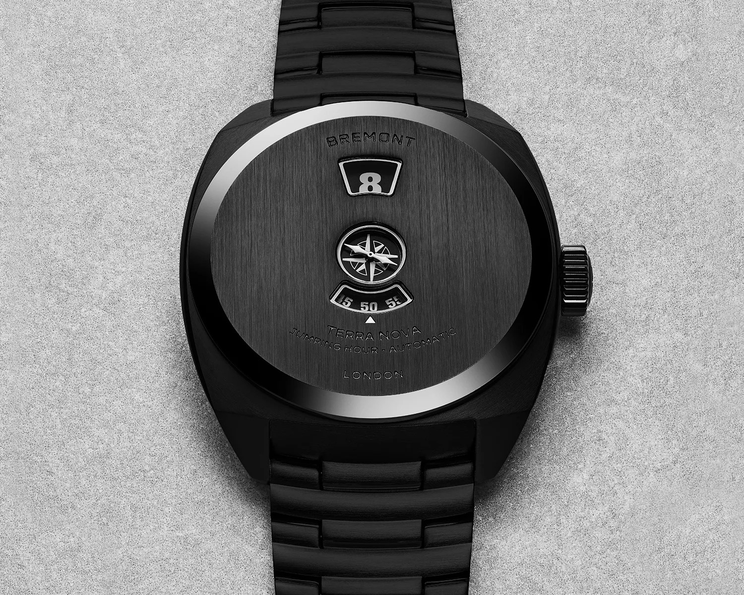 Black Bremont Terra Nova automatic watch with jumping hour display and compass rose detail on a black metal bracelet.