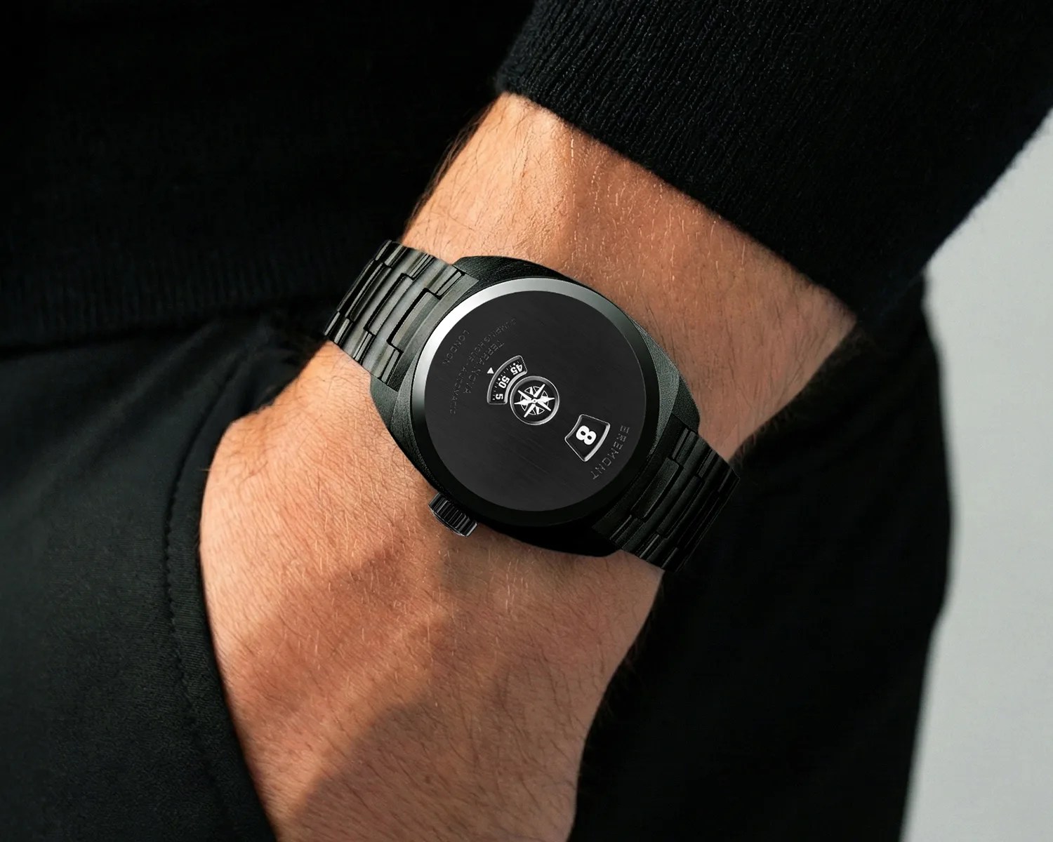 Black metal wristwatch with a round face and a digital date display worn on a wrist.