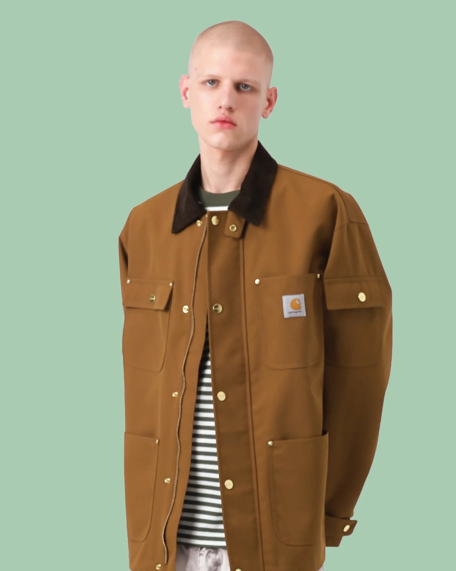 Brown Carhartt jacket with black collar and gold buttons worn over a striped shirt.