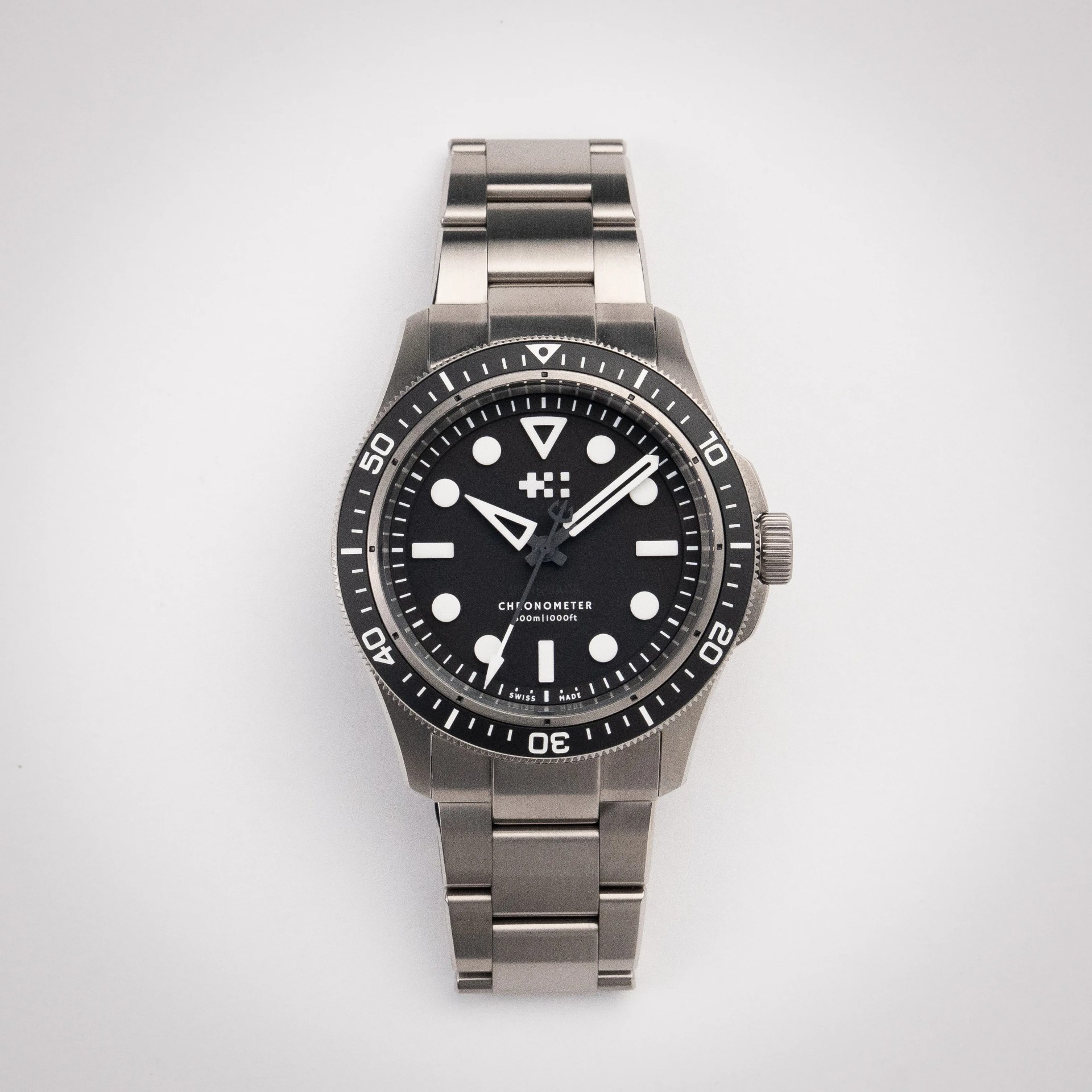 Stainless steel dive watch with black bezel, black dial, white markers, and metal link bracelet.