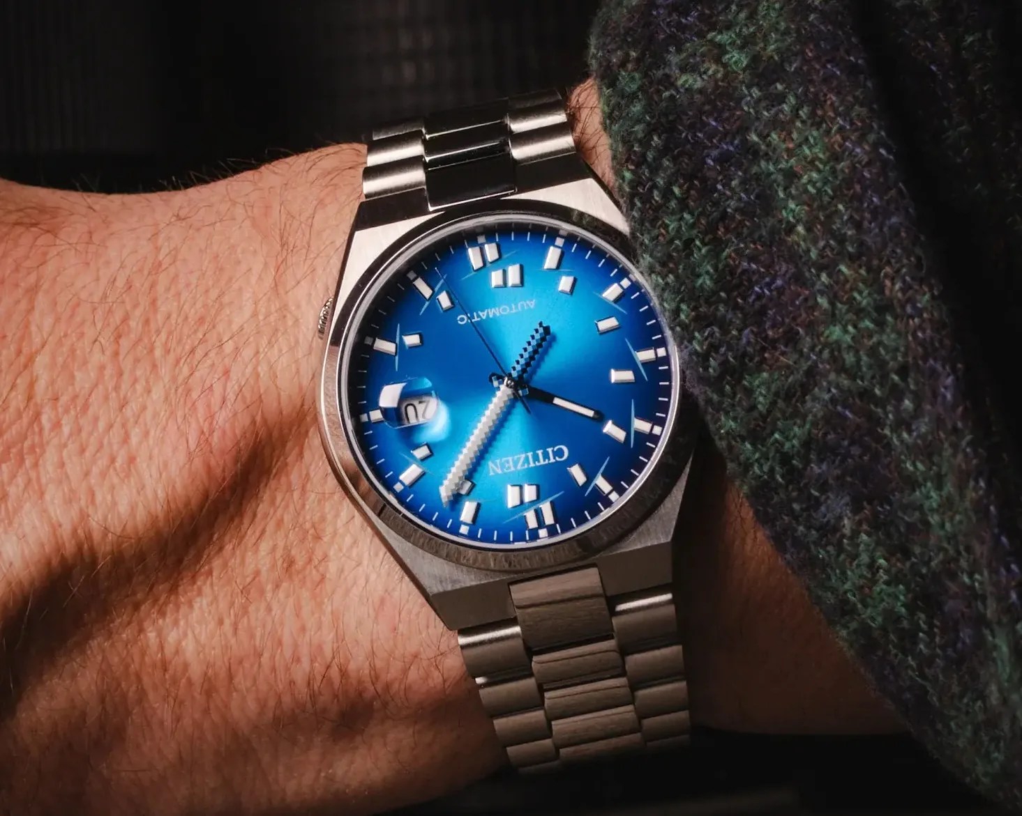 Silver Citizen automatic wristwatch with a blue dial and date window worn on a wrist.