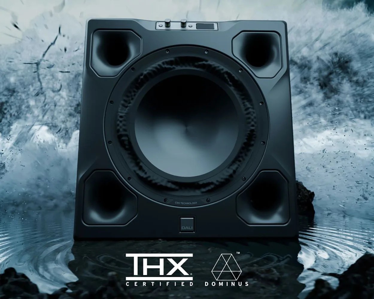 Black DALI Dominus subwoofer with four corner ports on a reflective water surface with THX Certified logo.