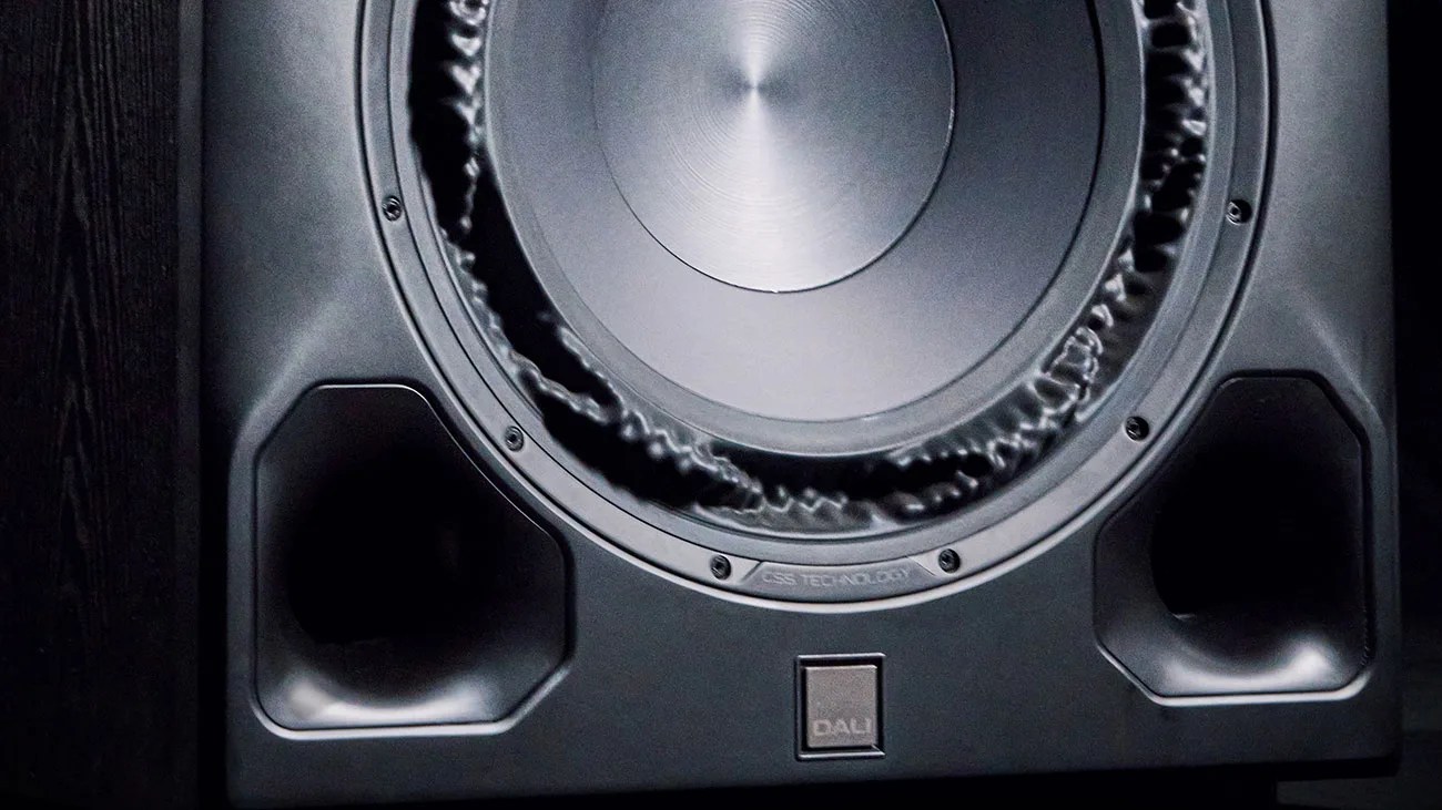 Close-up of a black DALI speaker with a large central driver and two port openings on the front panel.