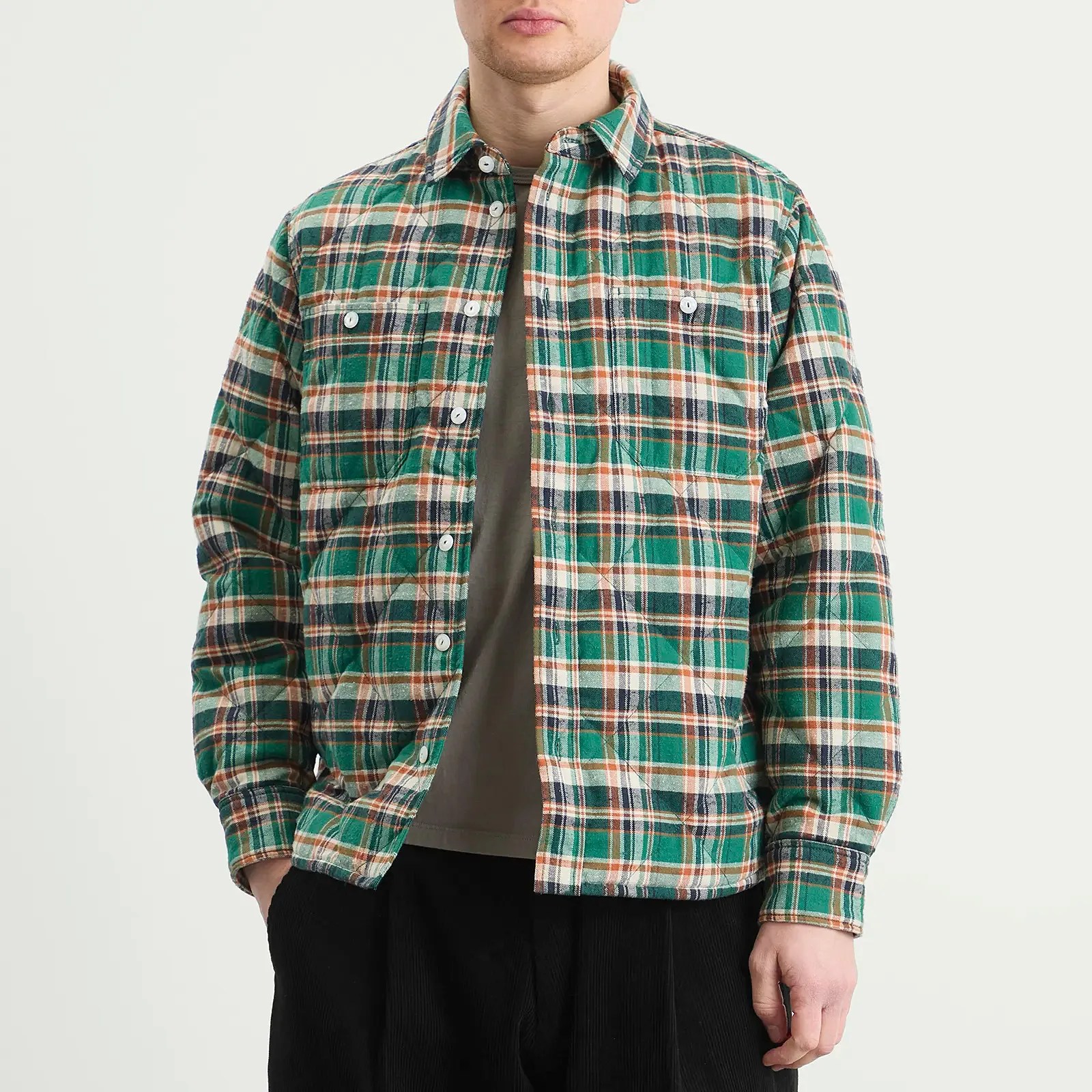 Green, white, and orange plaid button-up flannel shirt worn open over a gray t-shirt.
