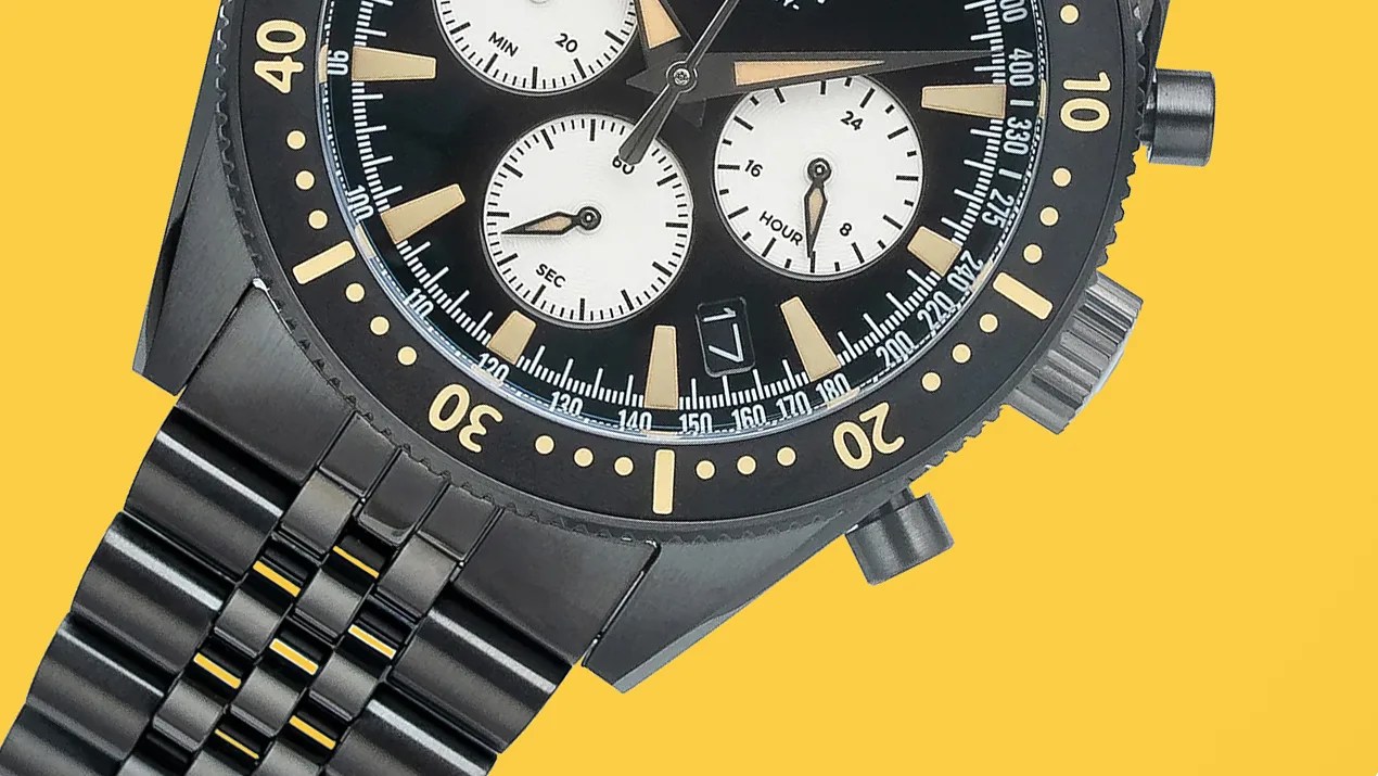 Black metal chronograph watch with beige markers and three white subdials on a yellow background.