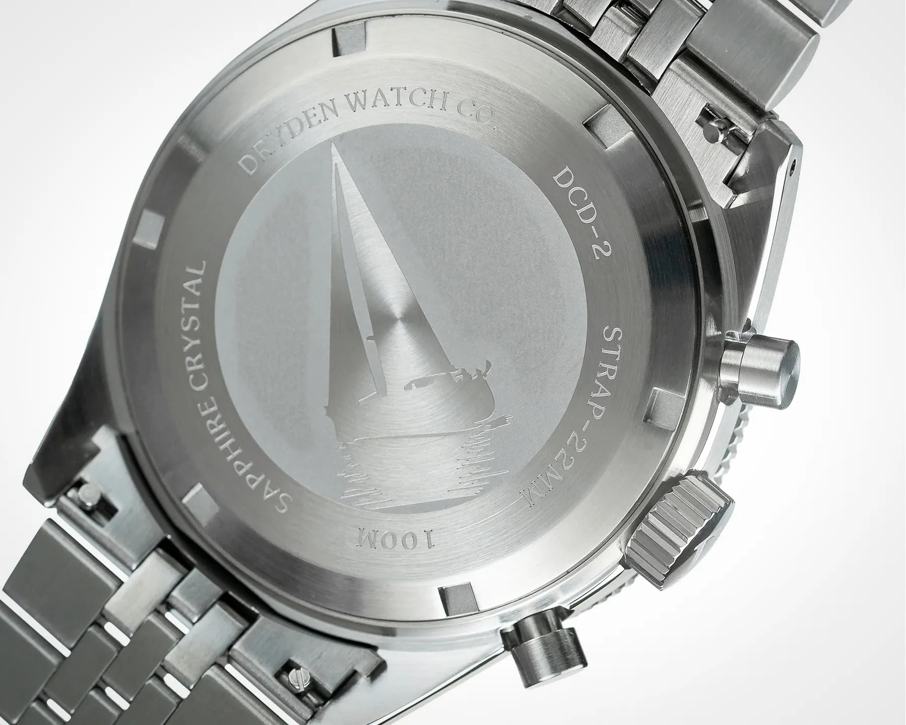 Back of a silver stainless steel watch case with an engraved sailboat and text including "DEWDEN WATCH CO," "SAPPHIRE CRYSTAL," and "100M.