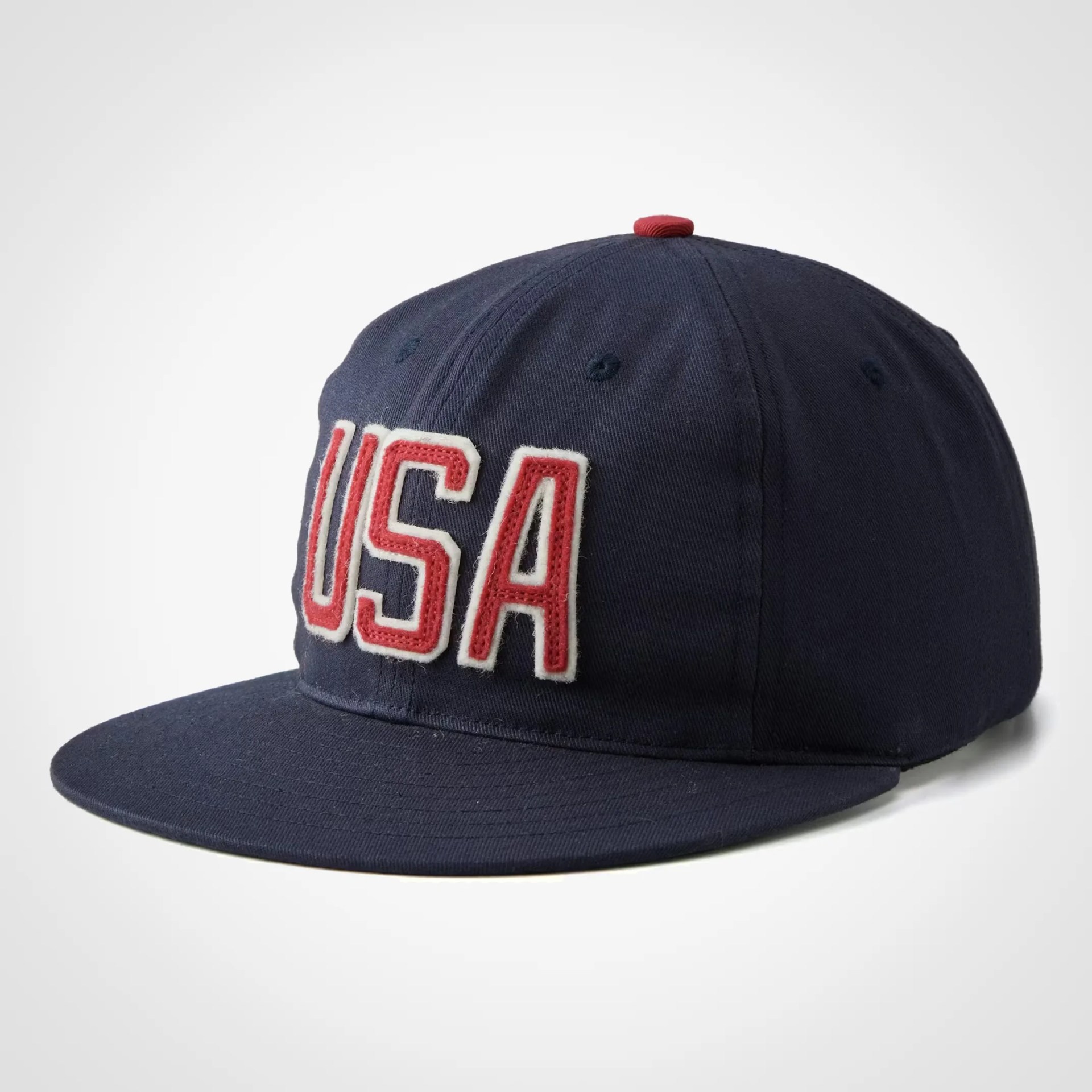 Navy blue baseball cap with red and white "USA" lettering on front and a red button on top.