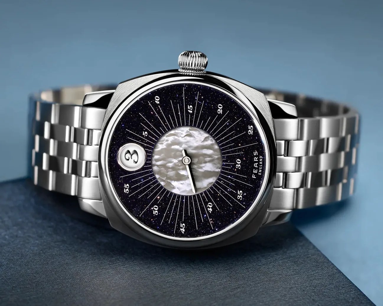 Silver metal wristwatch with a dark starry dial, mother-of-pearl center, and date window showing number 3.