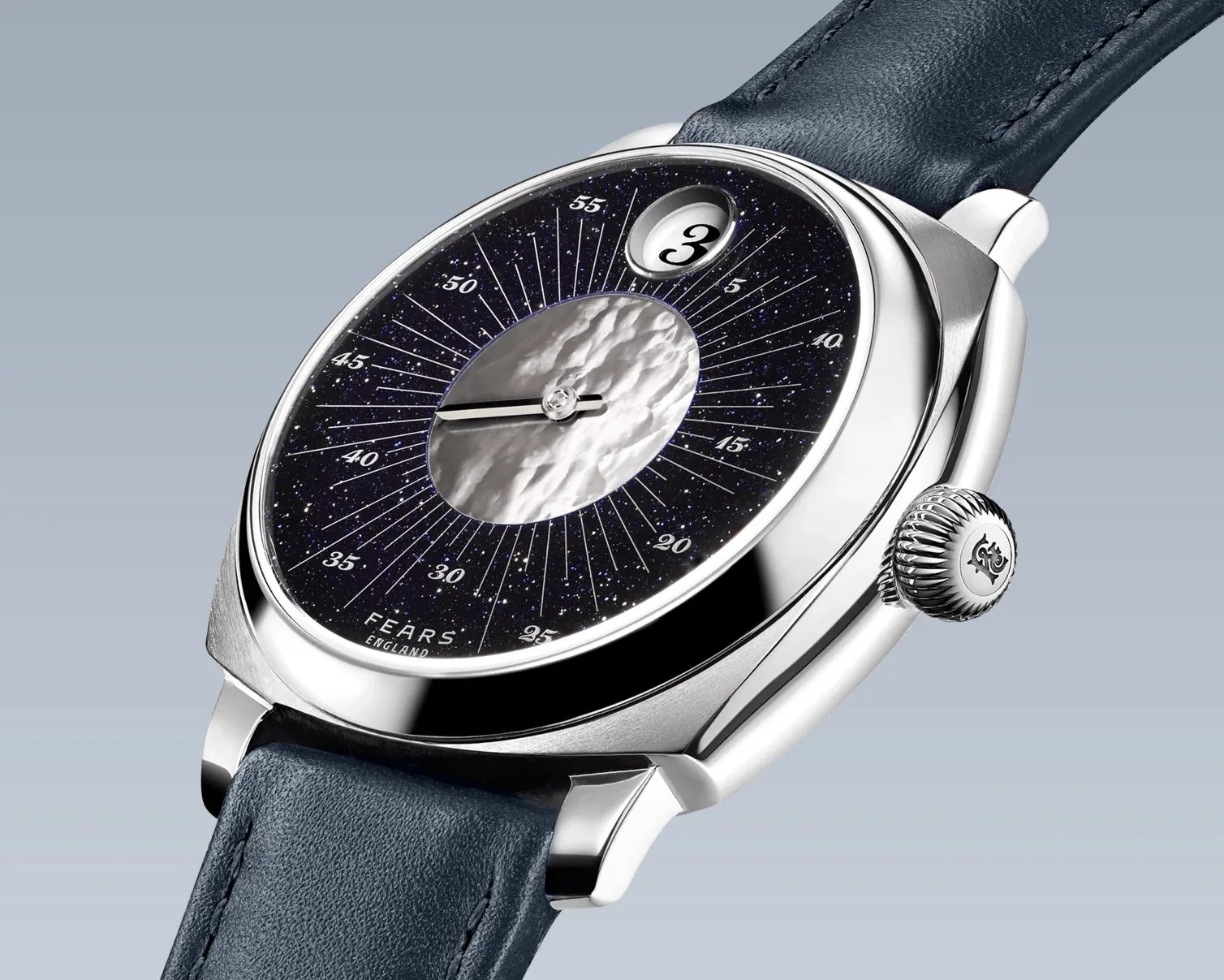 Silver wristwatch with a textured central dial, navy blue starry outer dial, date window at 1 o'clock, and blue leather strap.