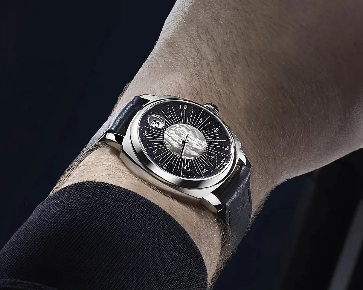 Silver wristwatch with a black starry dial and textured silver center, worn on a wrist with a black leather strap.