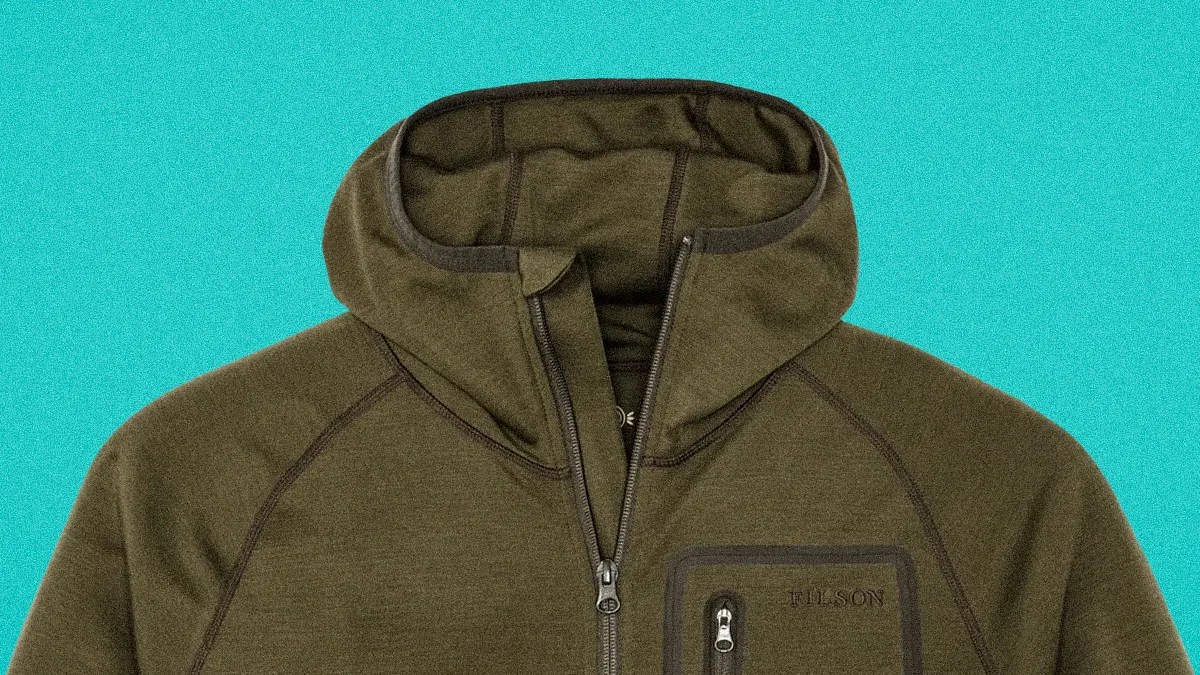 Olive green hooded jacket with front zipper and zippered chest pocket on a turquoise background.