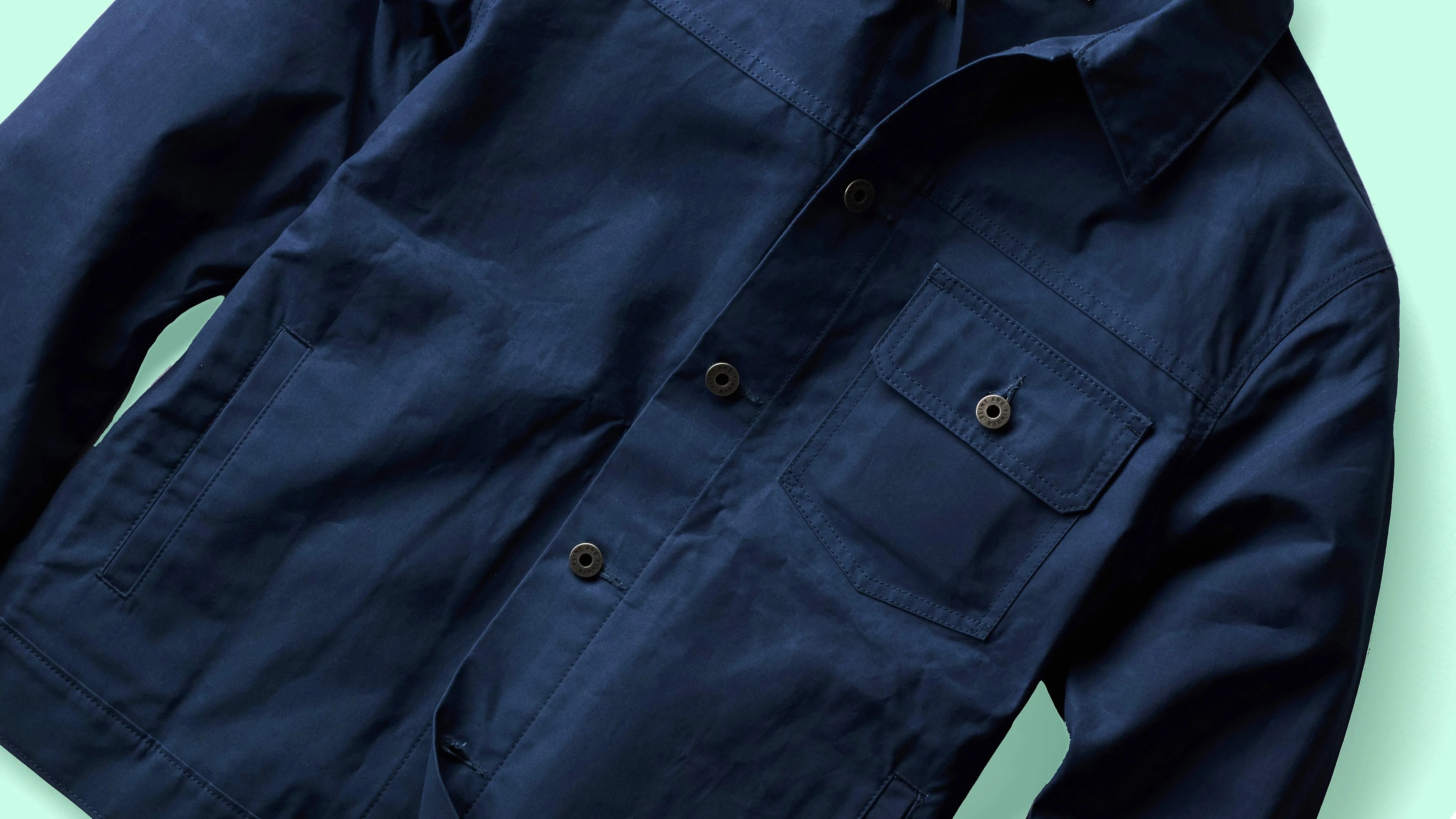Navy blue button-up jacket with a chest pocket and side pockets on a light background.
