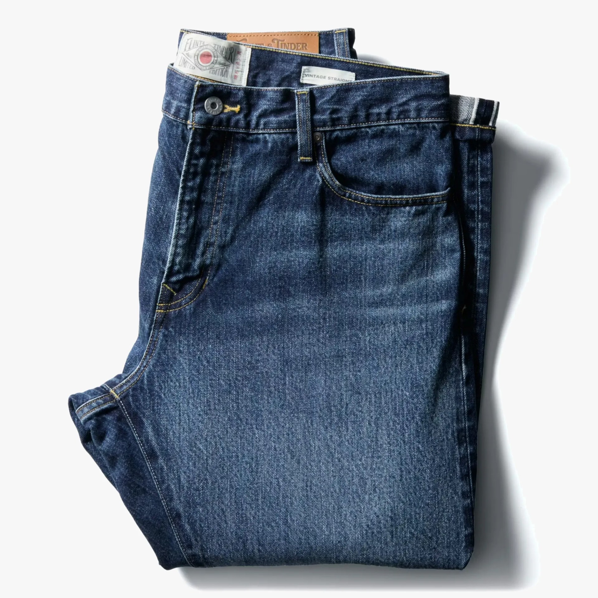 Folded dark blue denim jeans with visible front pockets and button closure.