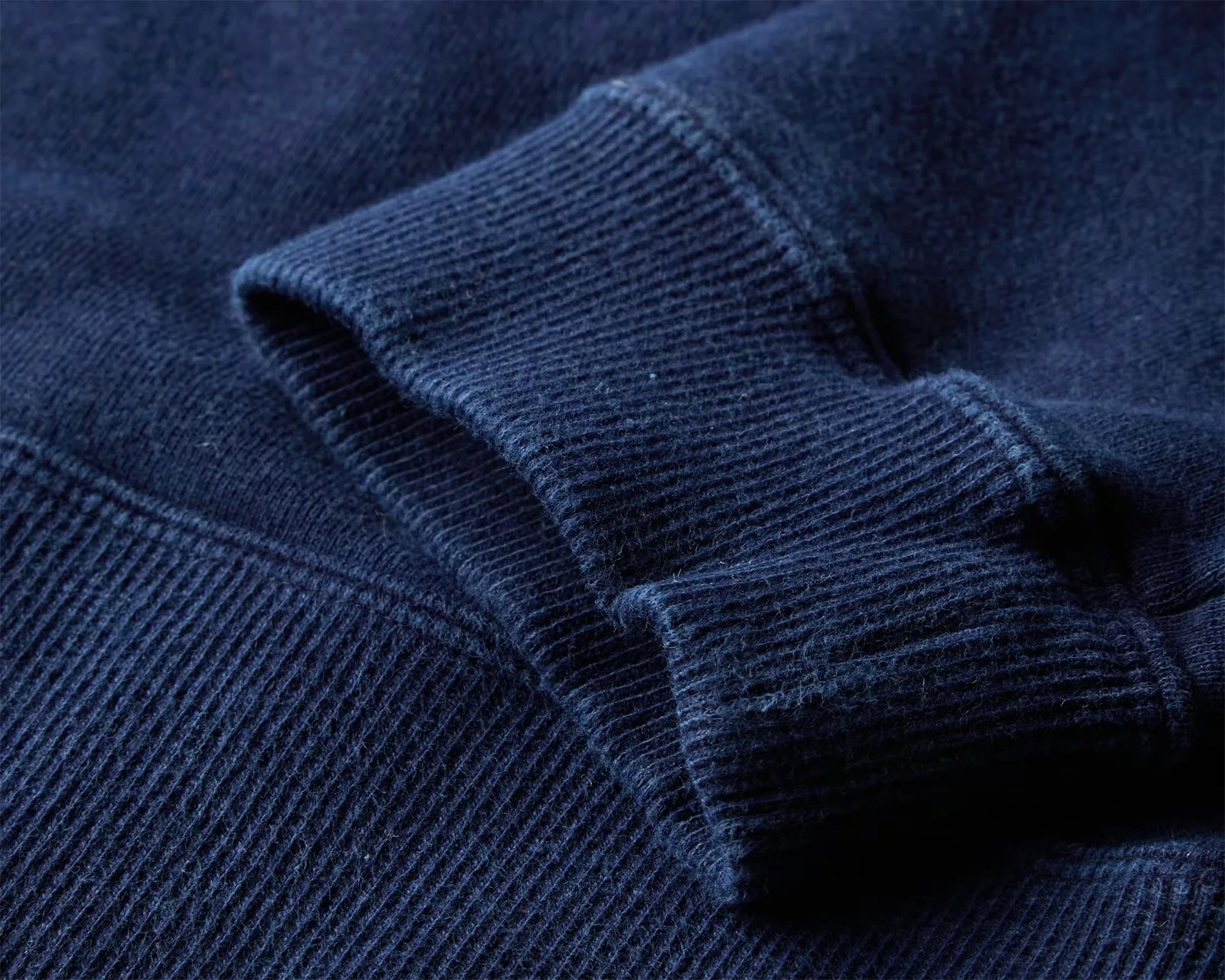 Close-up of navy blue ribbed knit fabric on a folded sleeve and cuff.