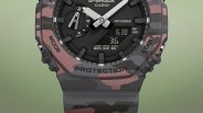 Close-up of a Casio G-Shock watch with a pink and gray camouflage pattern and digital-analog display.