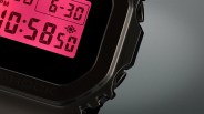 Close-up of a black digital watch with a red backlit display showing the time 10:58:50.
