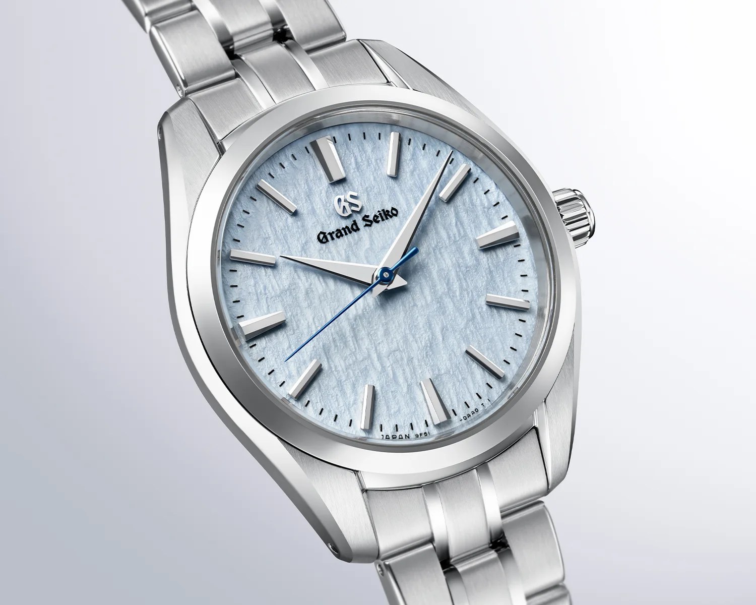 Silver stainless steel Grand Seiko wristwatch with textured light blue dial and blue second hand.