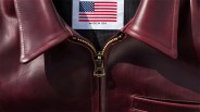 Close-up of a burgundy leather jacket with a brass zipper and a "Made in USA" label featuring an American flag.
