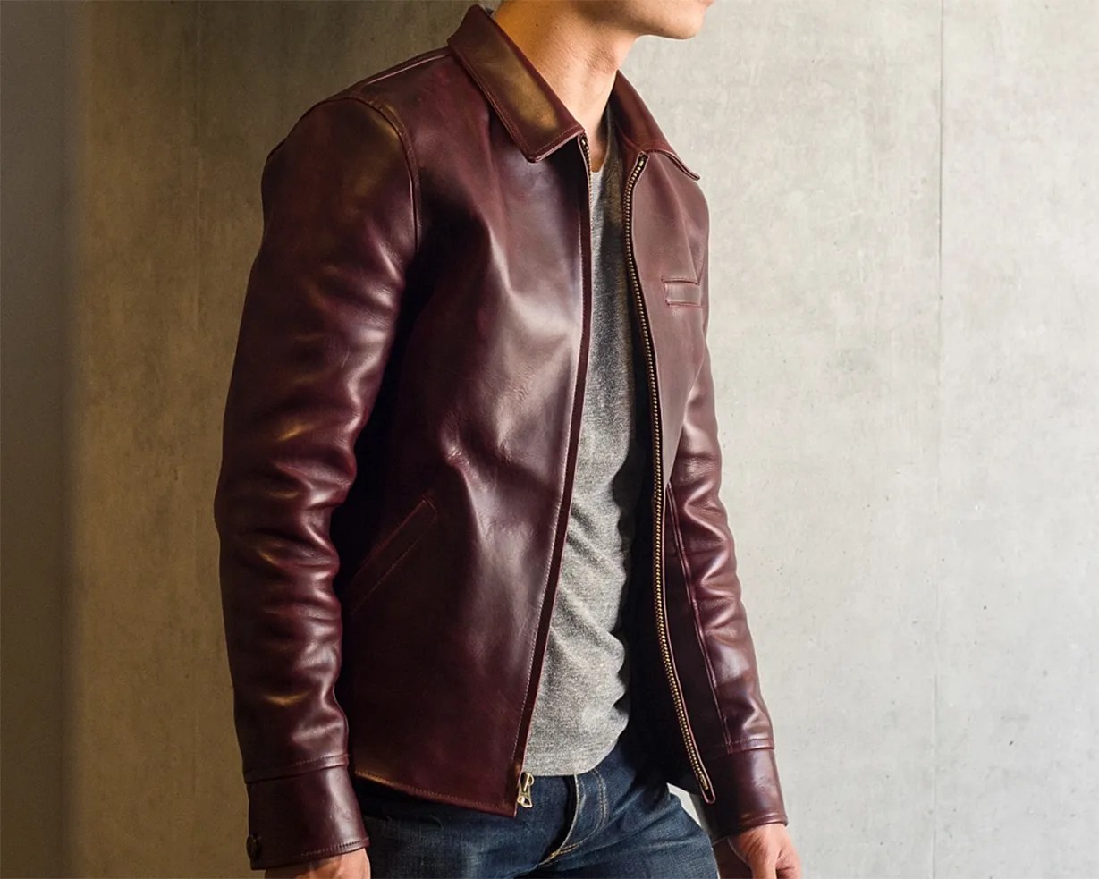 Burgundy leather jacket with zipper worn over a gray shirt and blue jeans.