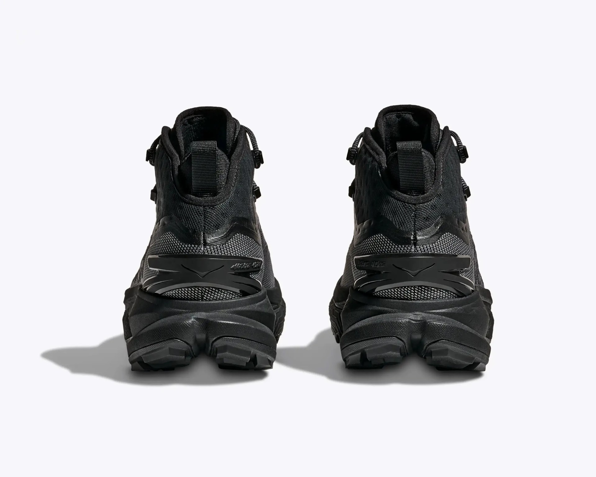 Pair of black athletic shoes with textured mesh uppers and thick rubber soles shown from the back.