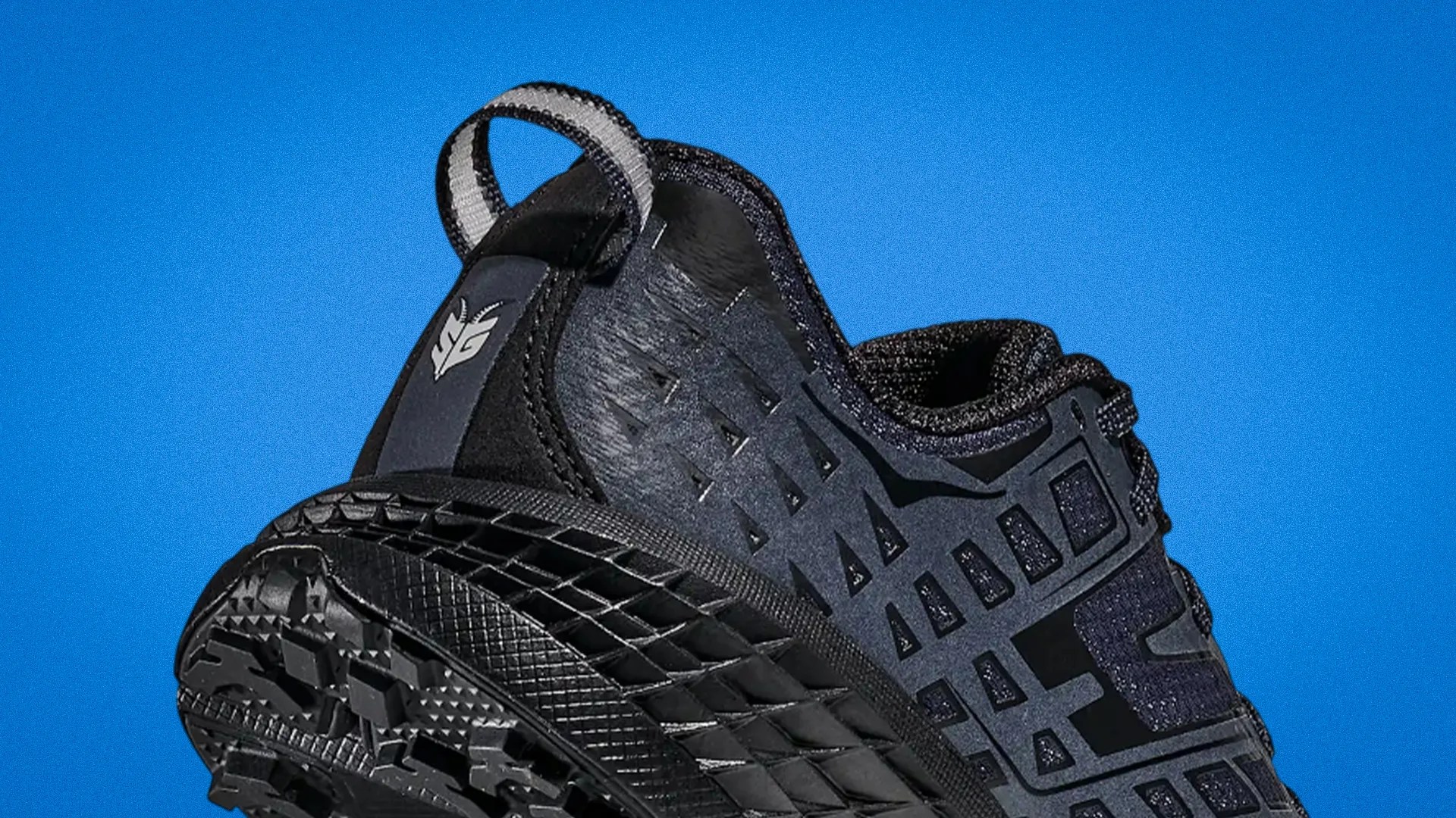 Black athletic shoe with textured sole and geometric cutout design on upper against blue background.