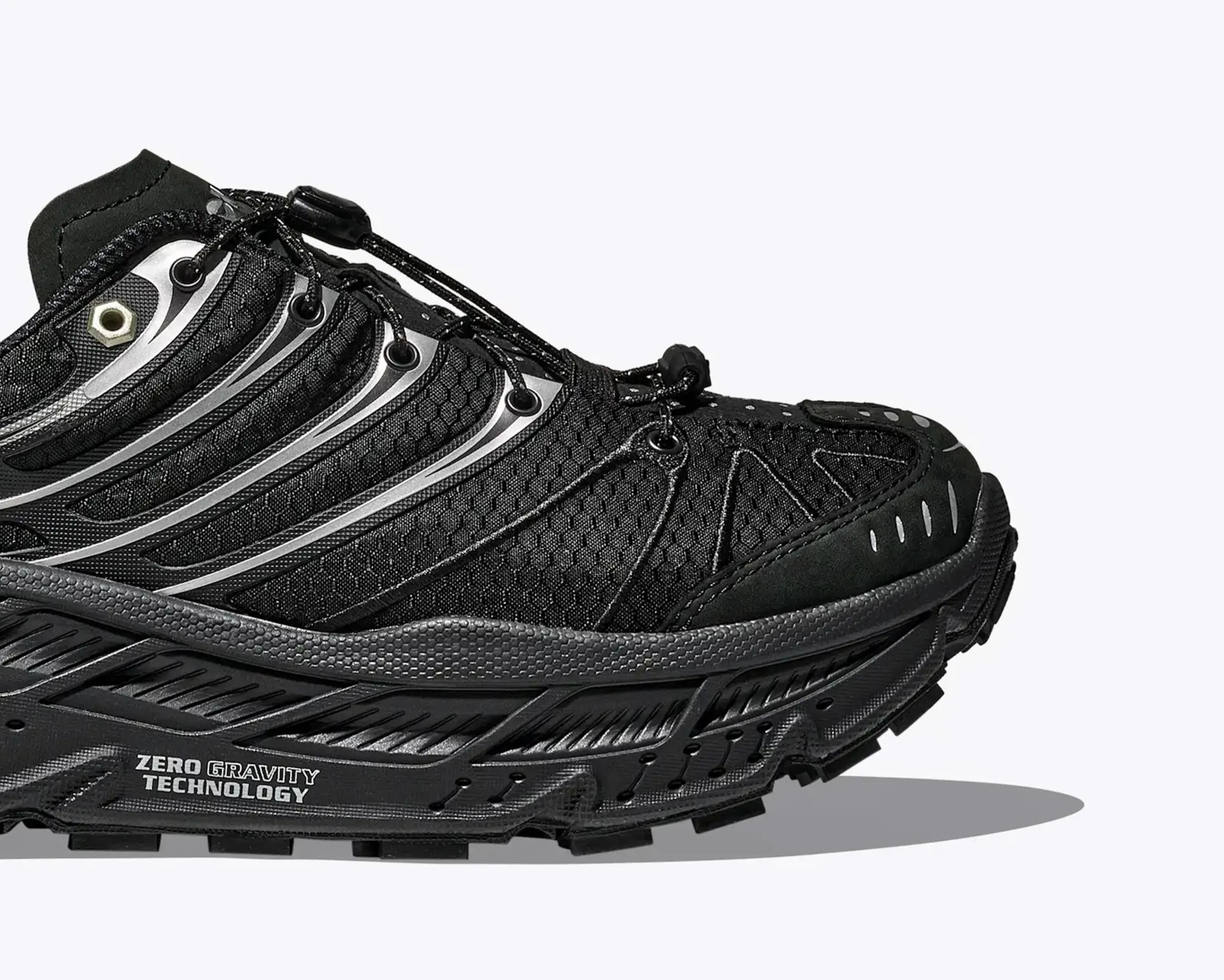 Black athletic shoe with hexagonal mesh upper, reflective silver stripes, and thick sole labeled "Zero Gravity Technology.