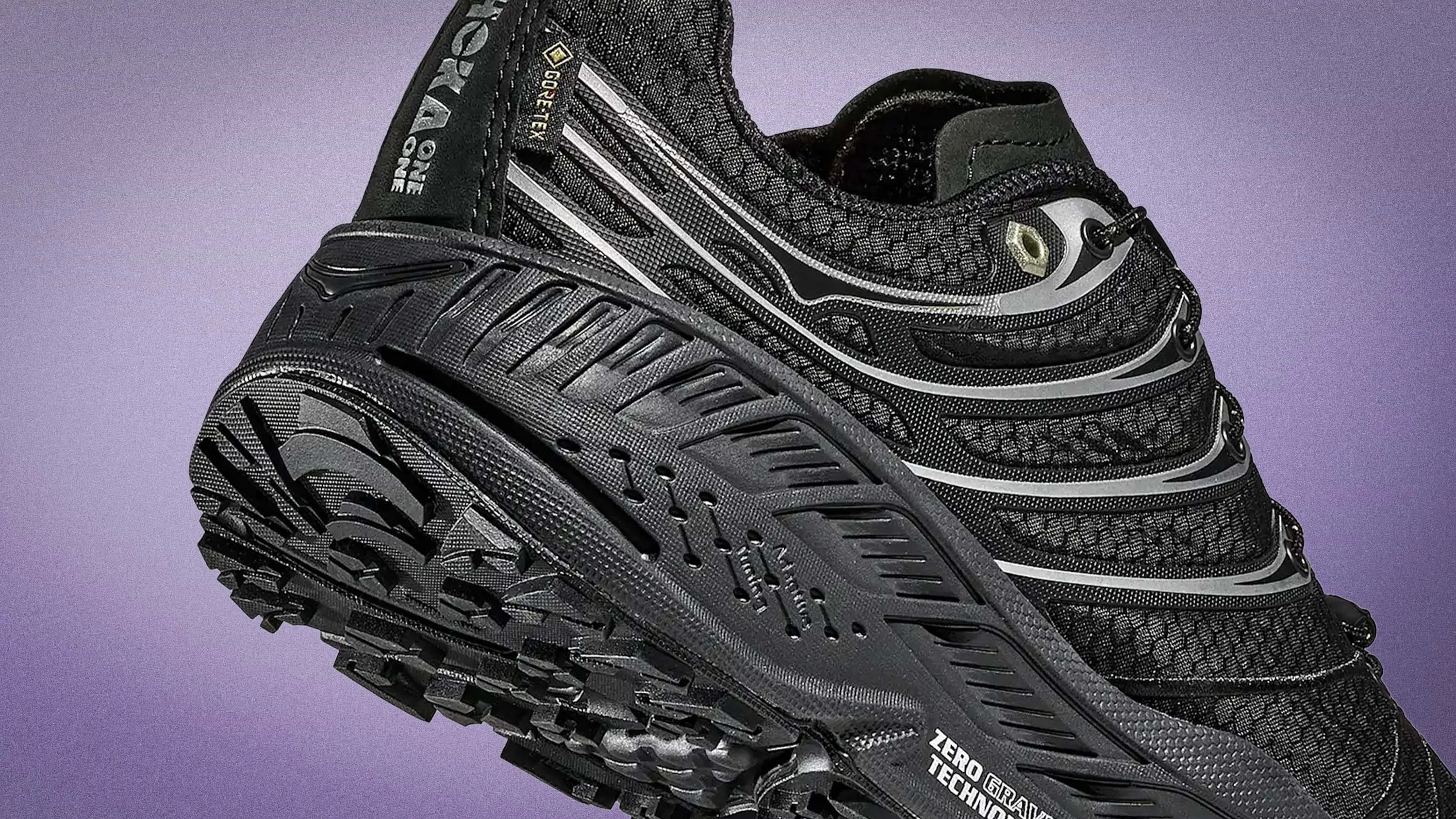Black Hoka One One trail running shoe with Gore-Tex upper and rugged outsole on a purple background.