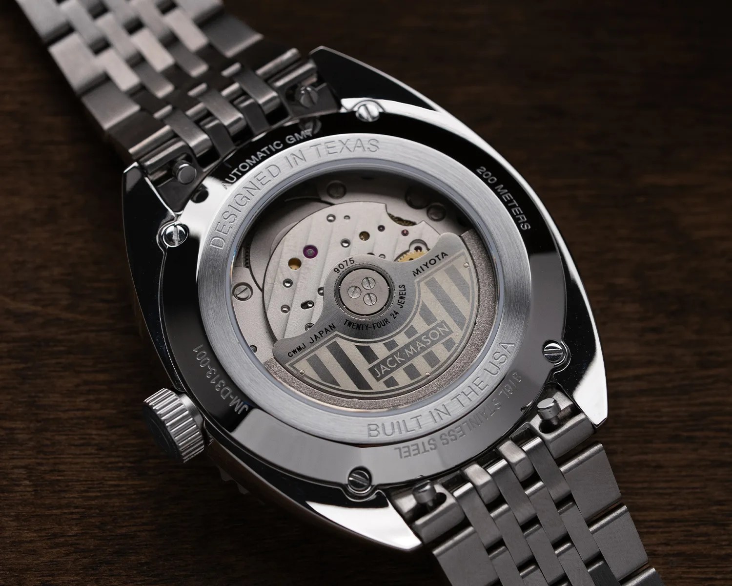 Close-up of the back of a stainless steel automatic watch with visible Miyota movement and engraved text "Designed in Texas" and "Built in the USA.